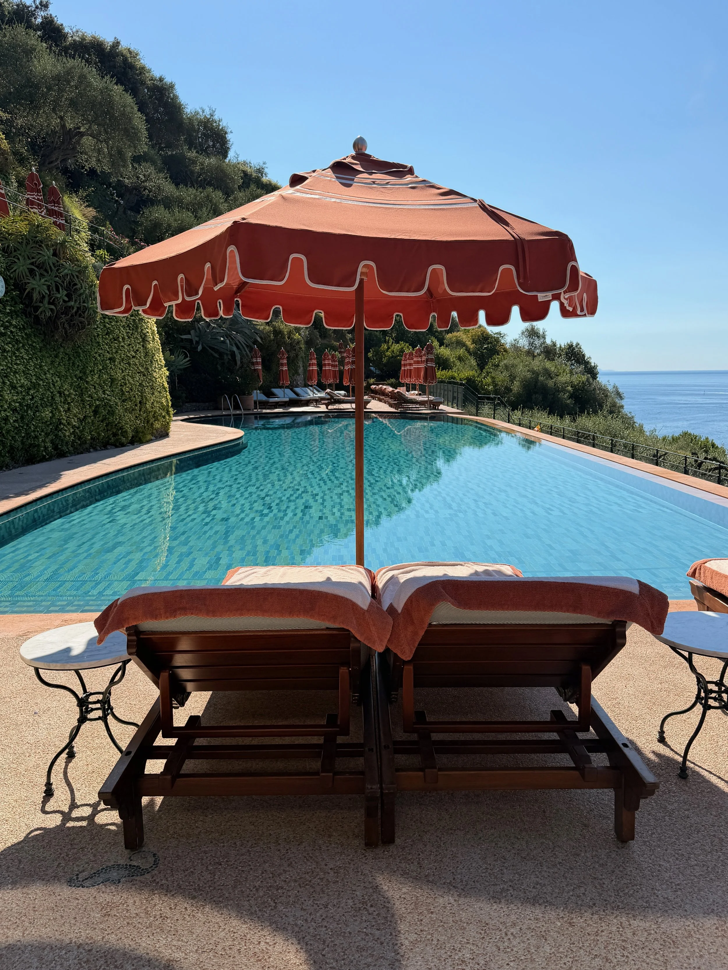 Terracotta parasol and loungers beside the sea view swimming pool at Splendido in Portofino