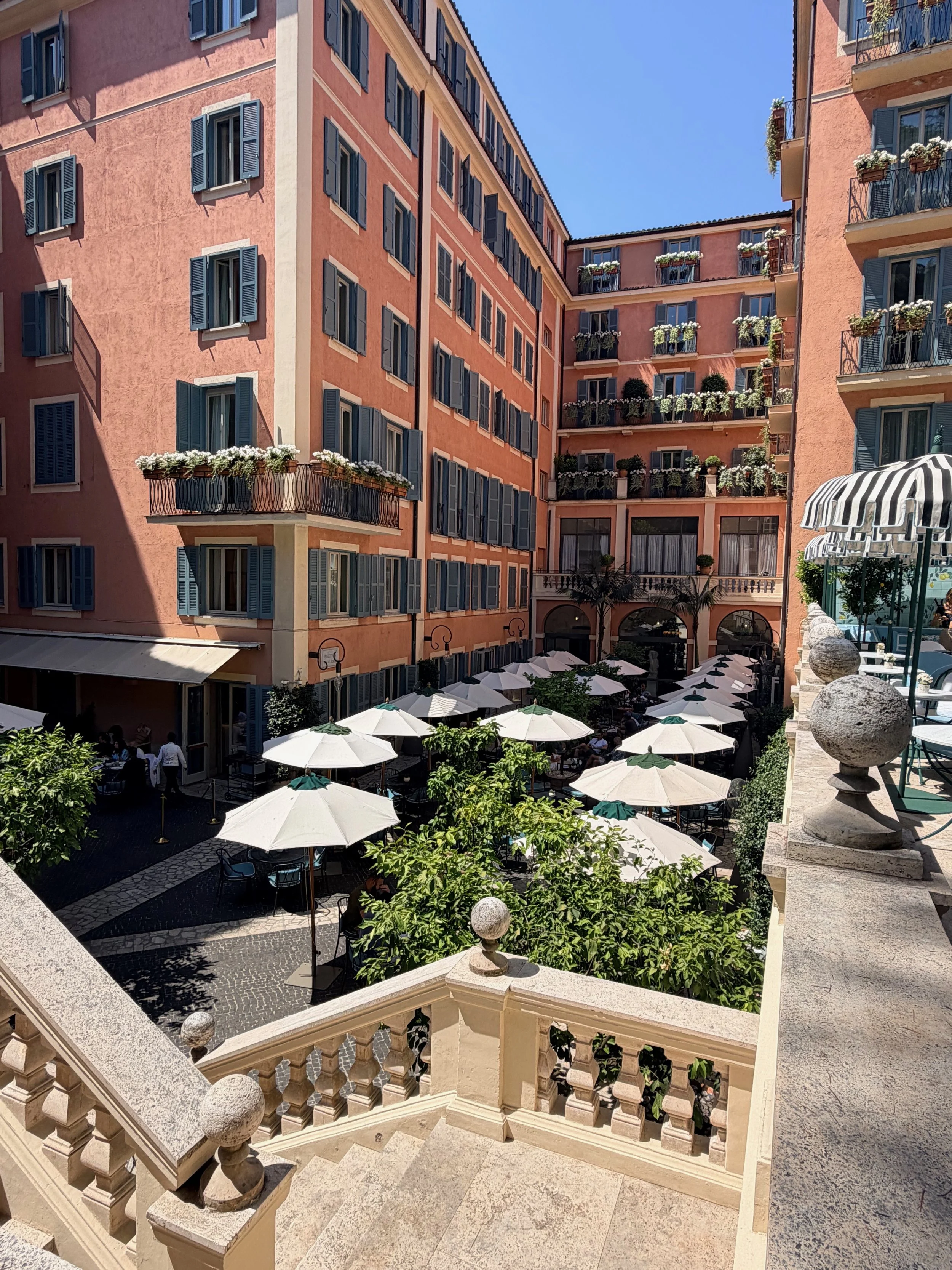 Terraced garden courtyard with white umbrellas at Hotel de Russie in Rome