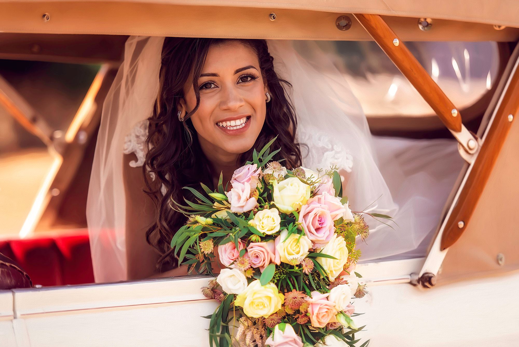 Fine art wedding portrait of a bride holding her bouquet, sitting in a beautiful classic car 