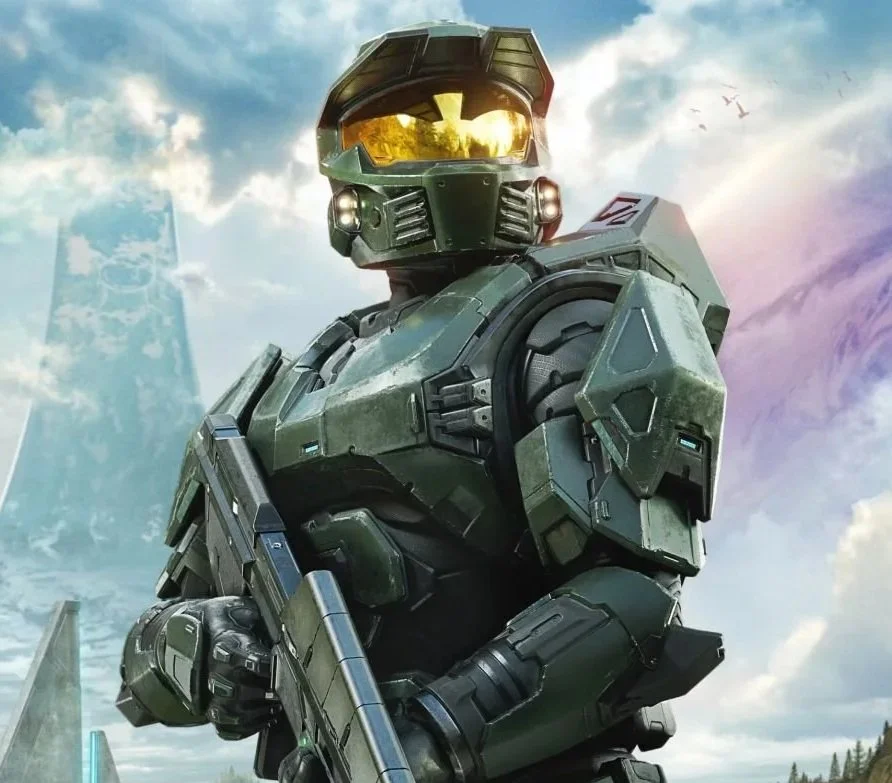 A person in green futuristic armor and helmet holding a gun, with a city skyline and cloudy sky in the background.