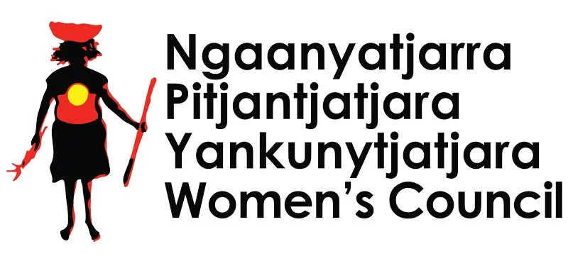 Logo of Nakanyatjara Pitjantjatjara Yankunytjatjara Women's Council featuring a stylized silhouette of a woman in traditional attire holding a stick, with bold black text.