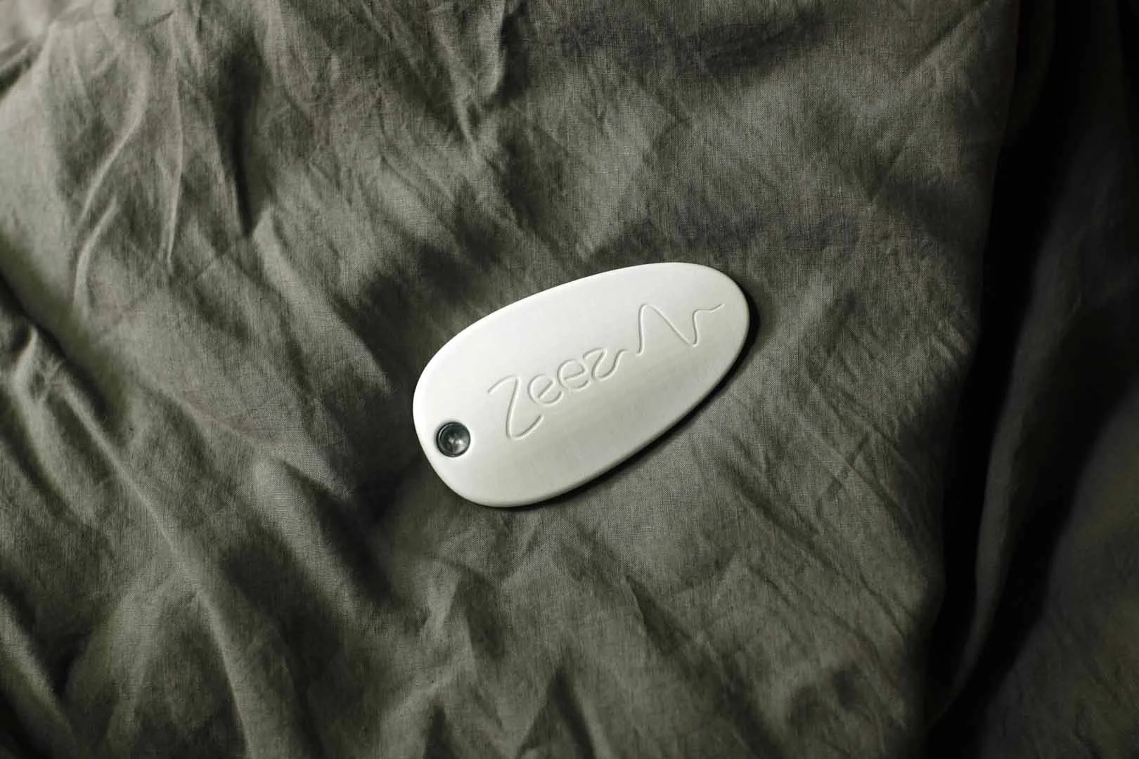 Zeez Sleep Pebble on grey bedsheet