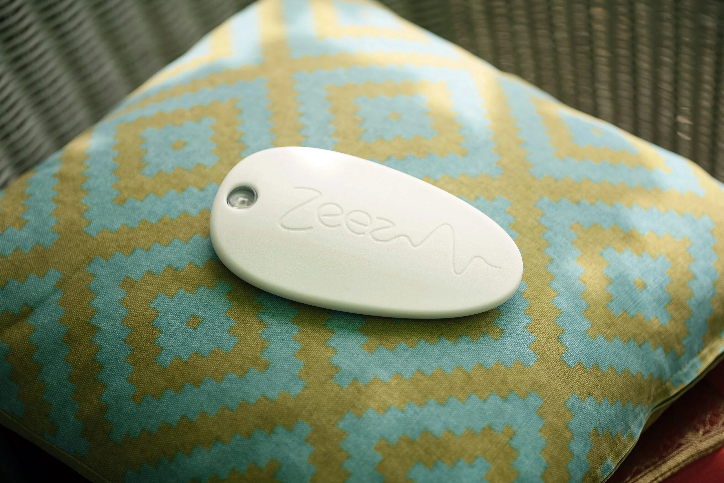 The Zeez Sleep Pebble on a patterned cushion