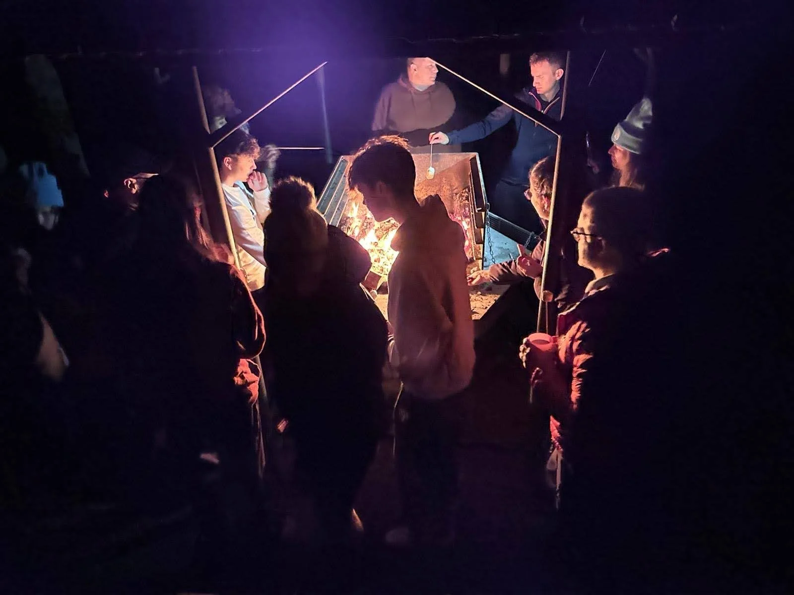 Children enjoy time together around a fire pit, it's dark and evening
