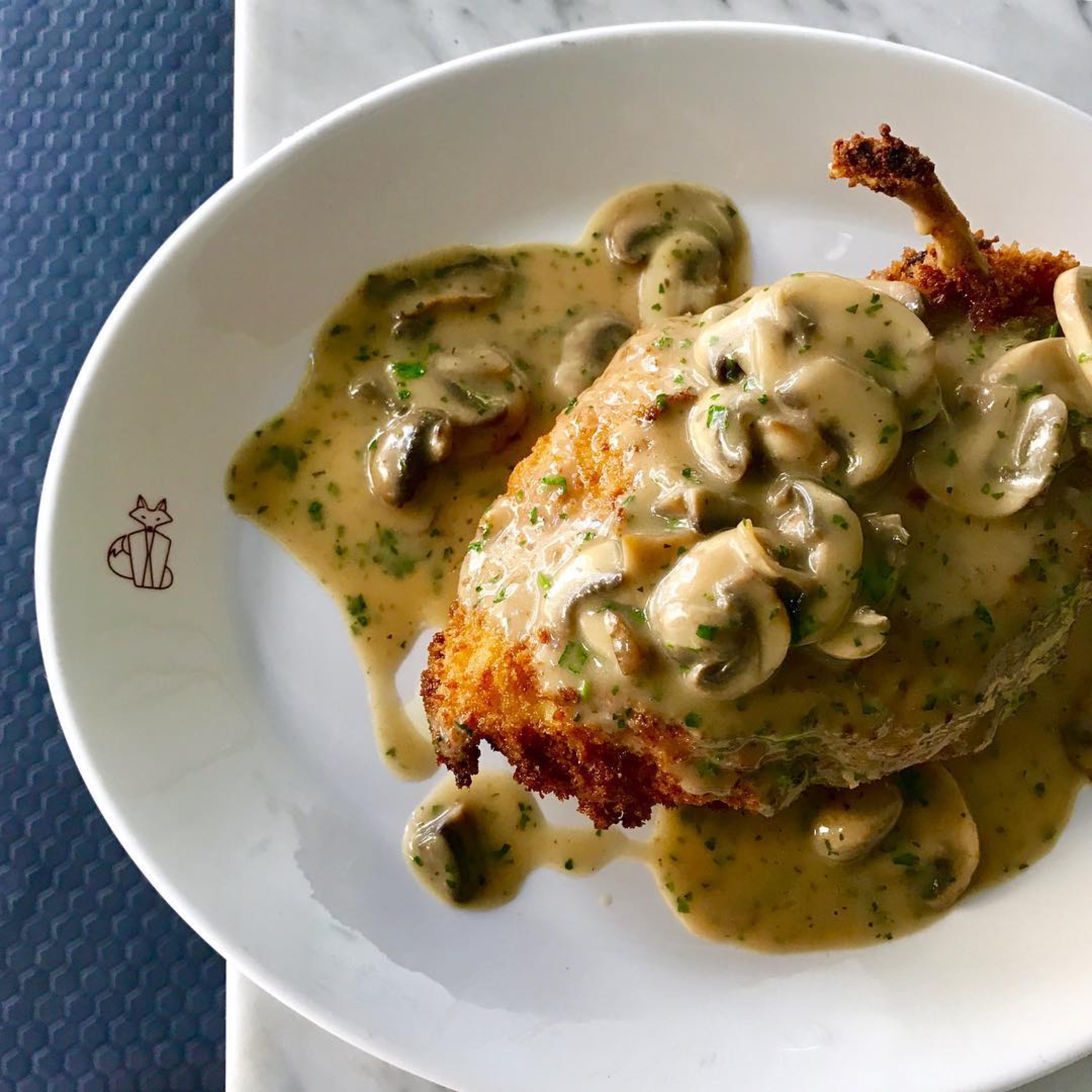  plate of fried chicken topped with creamy sauce suprême and mushrooms 