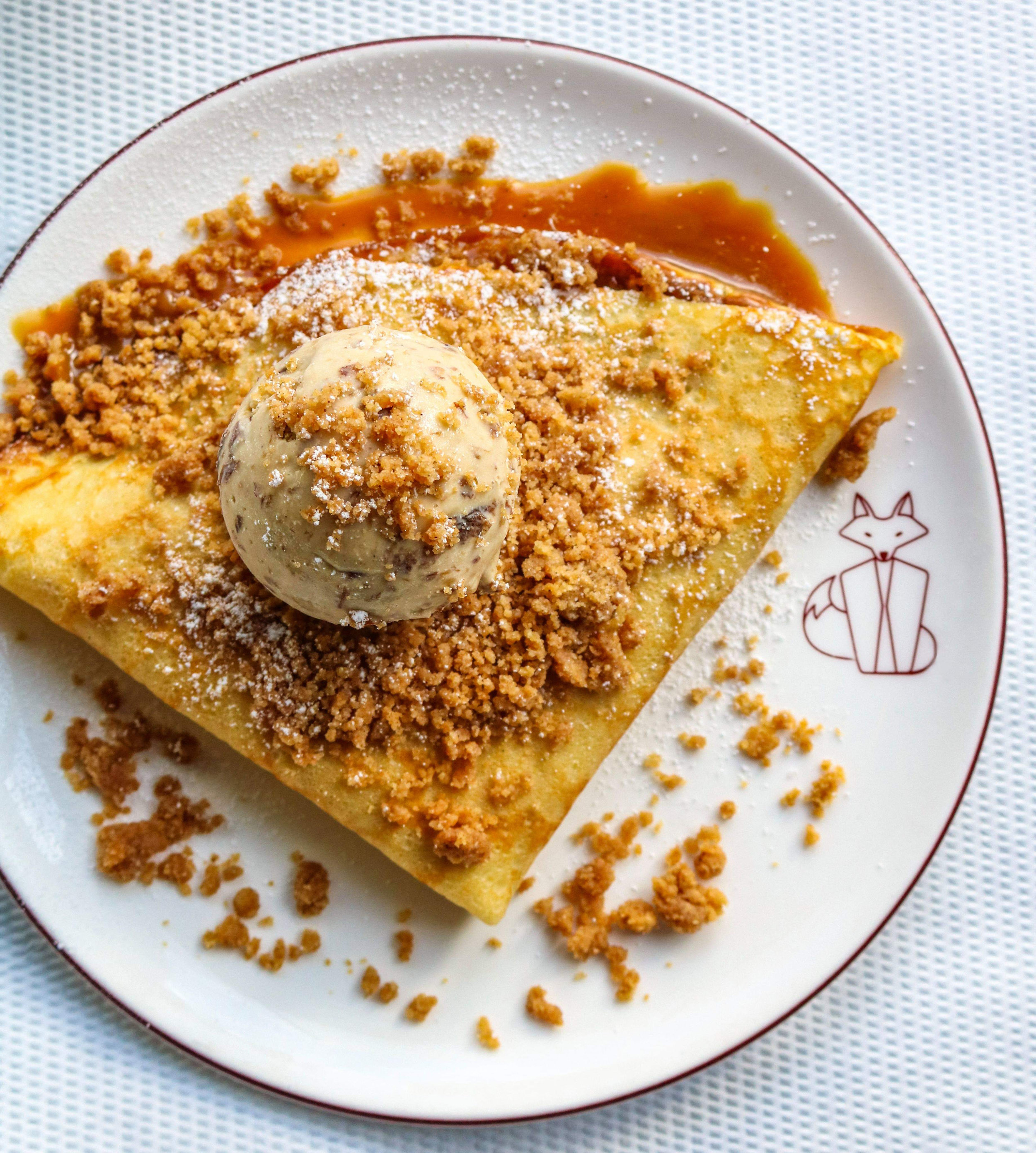  plate of banana crepe, folded into a triangular quarter topped with rum raisin ice cream and cinnamon streusel 
