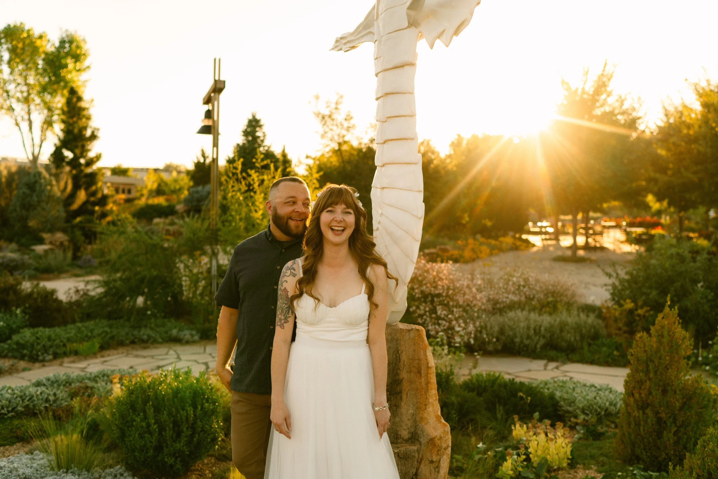 Adam and Mallory Johnson at their wedding reception, smiling in front of a setting sun.