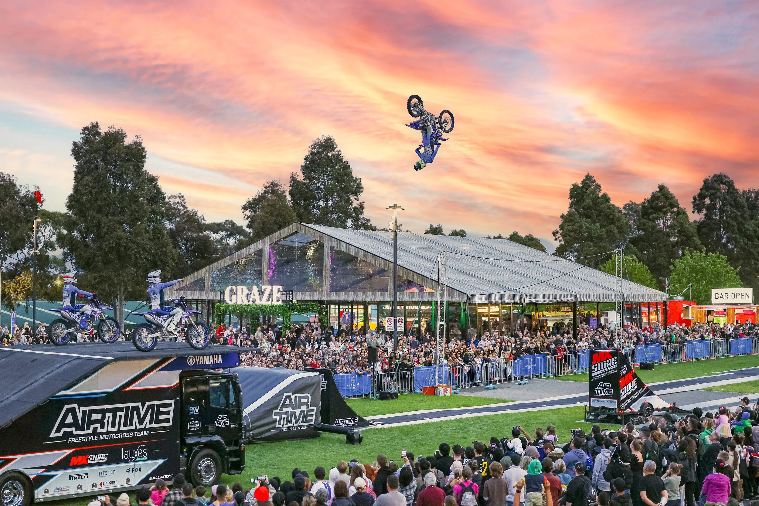 Melbourne Royal Show event photography capturing a spectacular motocross stunt performance by Airtime FX in front of a large crowd at sunset.