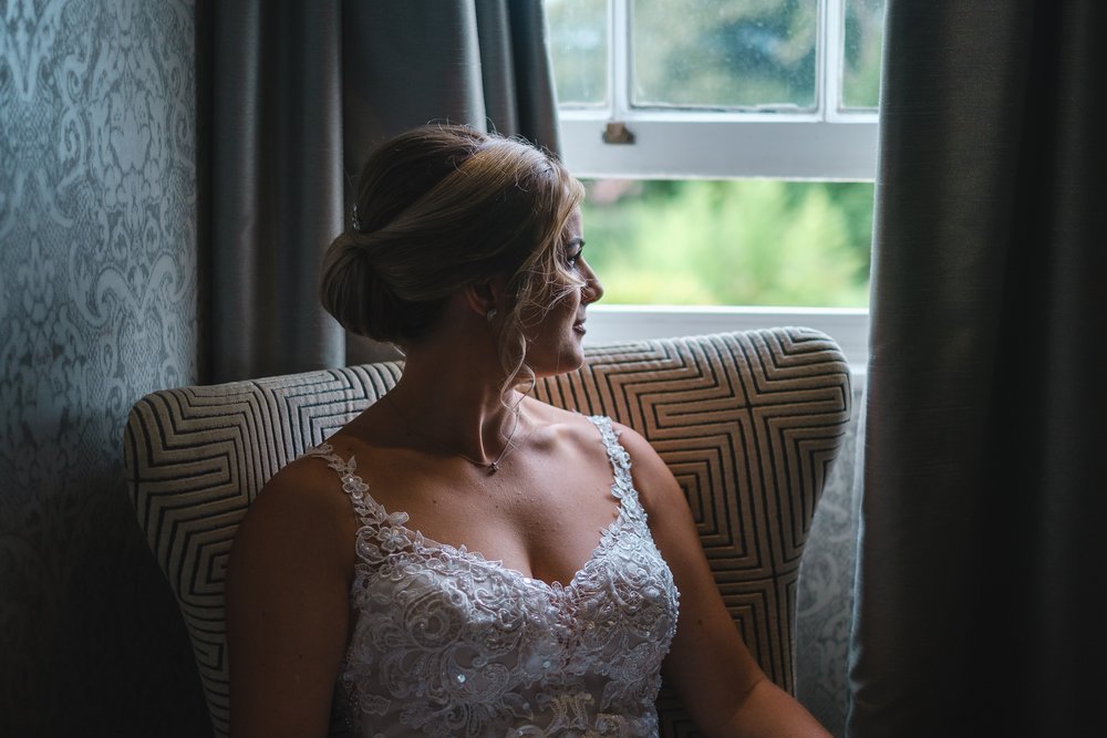 Bridal portrait of a bride sitting by a window