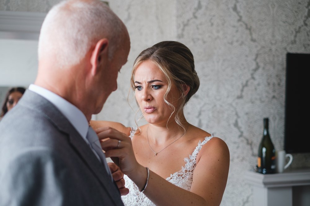 Bride putting the buttonhole on her dad's suit