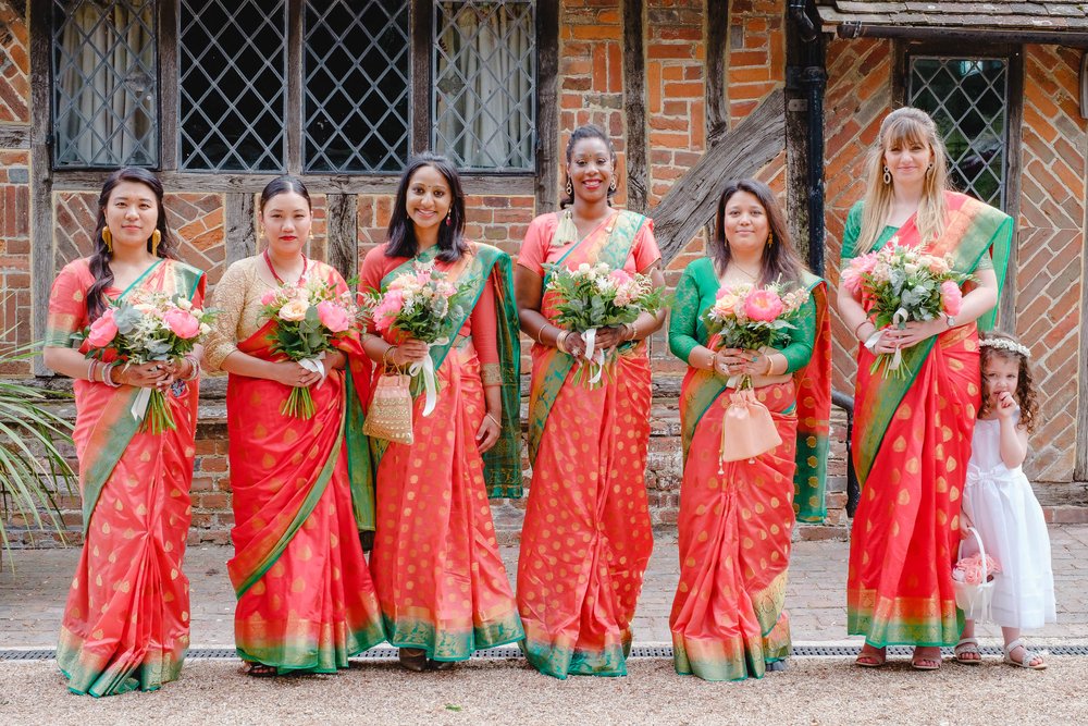 Bridesmaids in colourful red print dresses at a Buddhist wedding