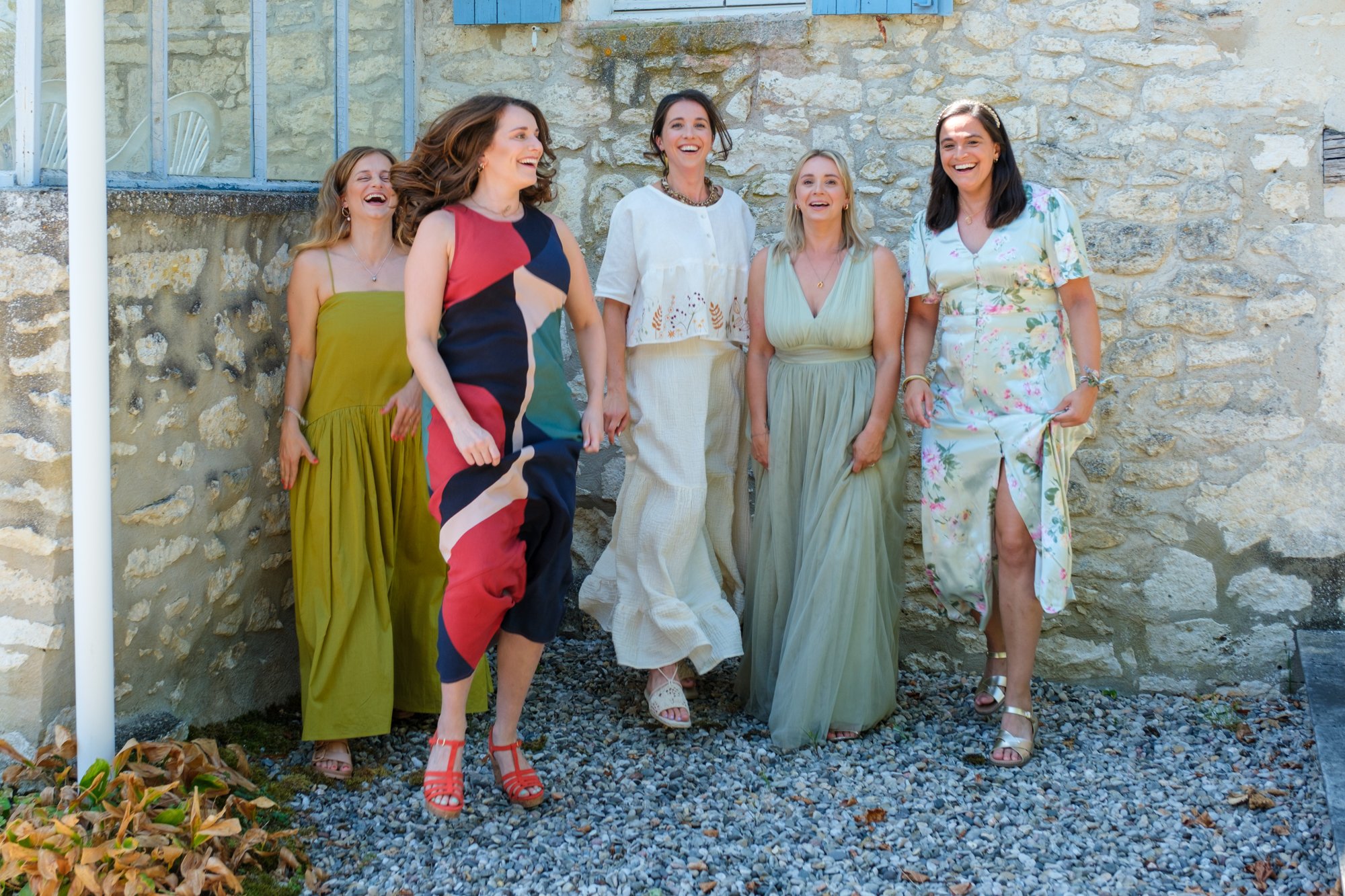 Bride and her bridesmaids in different coloured green dresses tracing towards the camera