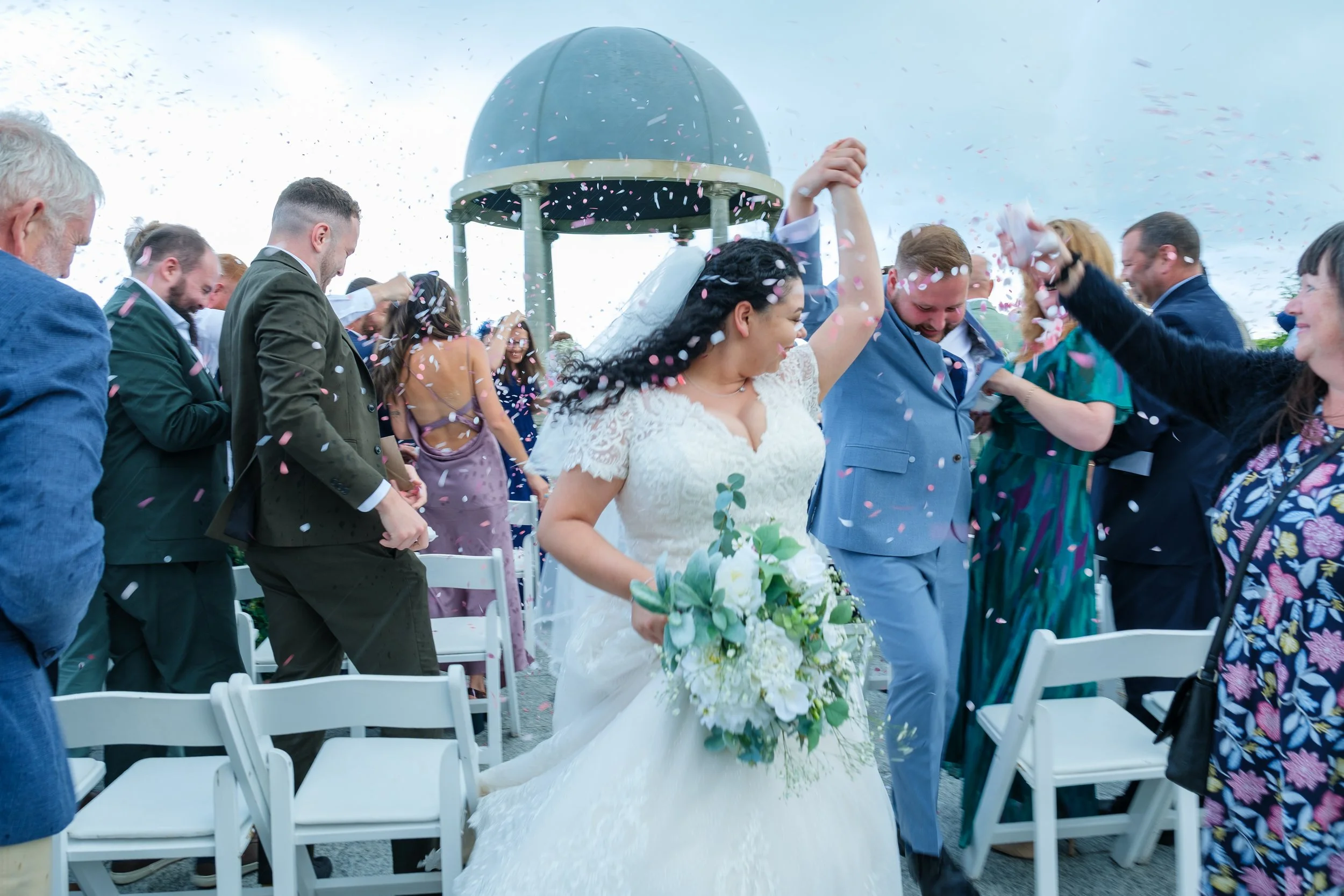 Bride and groom running through confetti and rain
