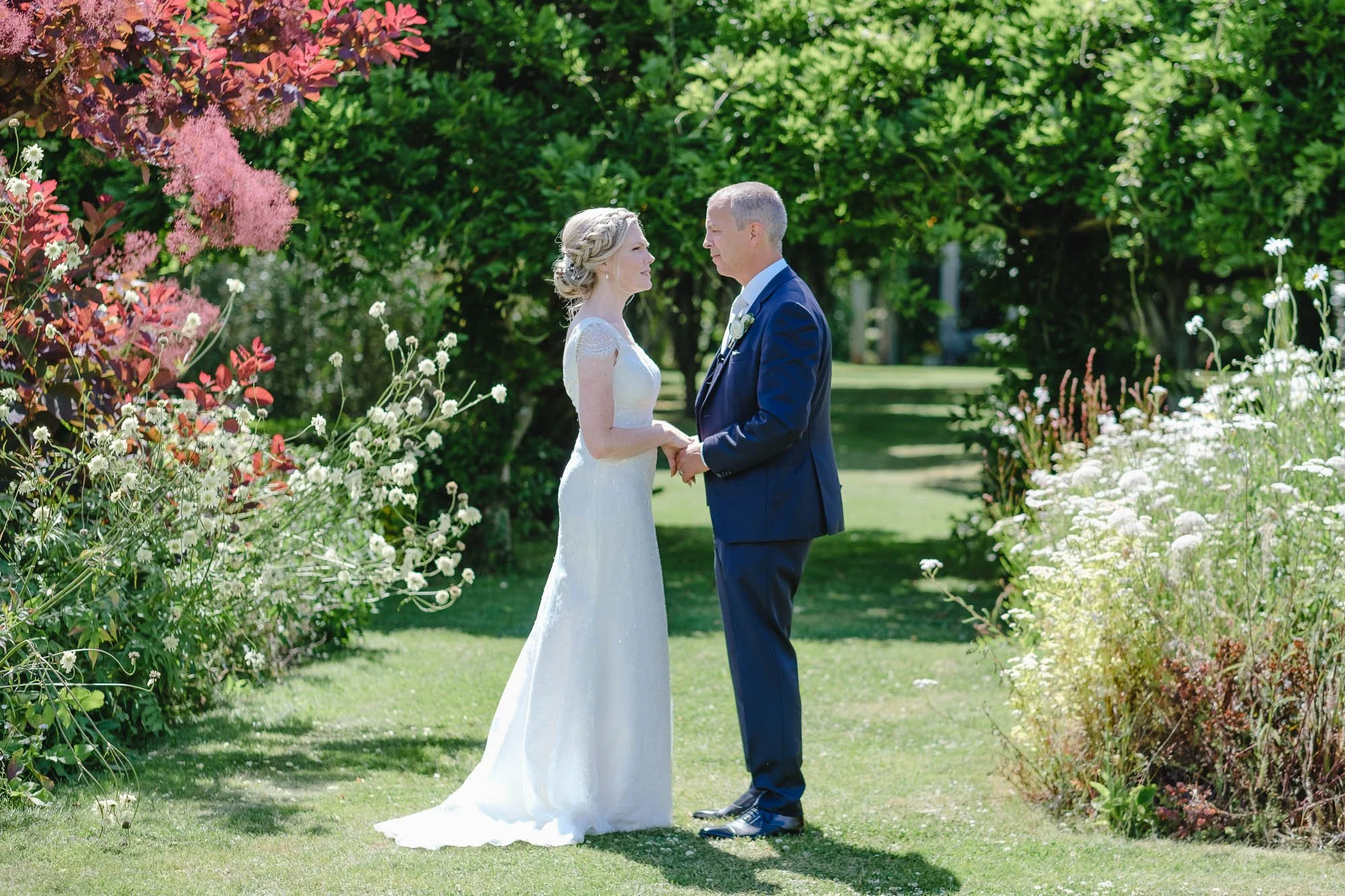 Bride and groom holding hands and staring at each other in the garden of The Gardens Yalding after their wedding ceremony.