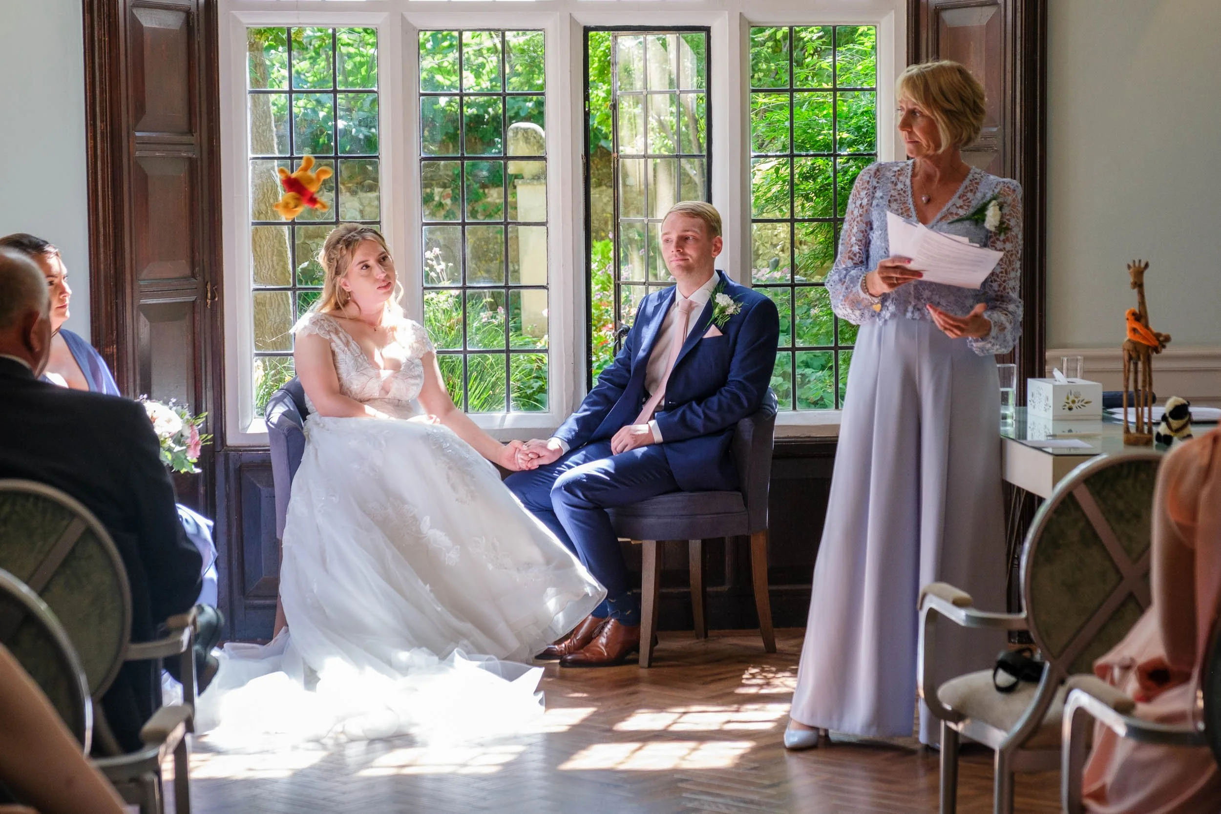 Bride and groom sitting in one of the rooms at Lewes registry office whilst the mother of the bride does a reading and casually tosses a soft toy across the room