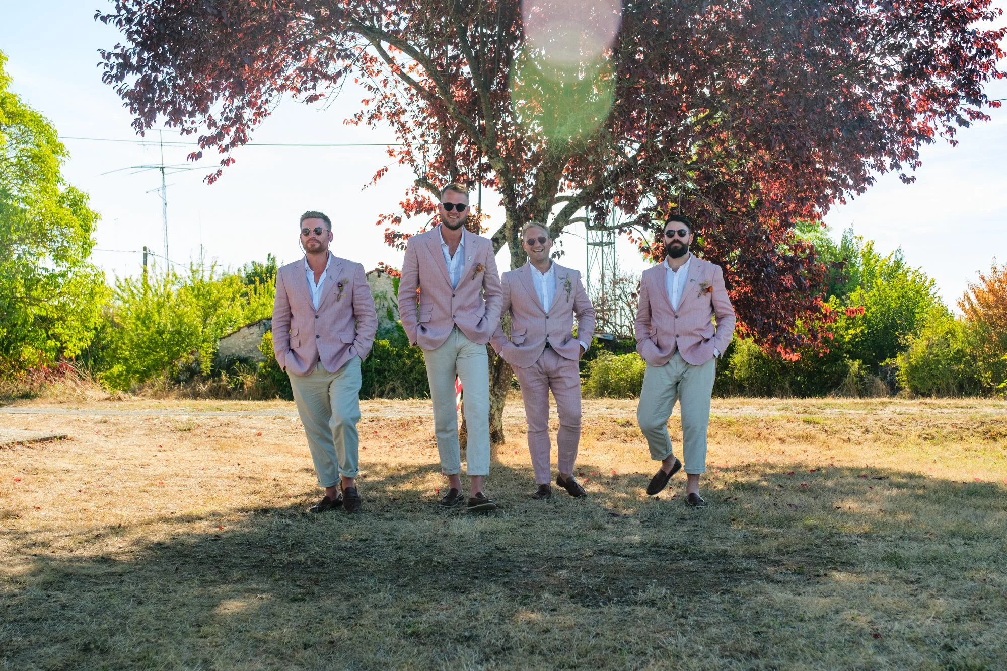 Groom and groomsmen in pink suits walking in a line