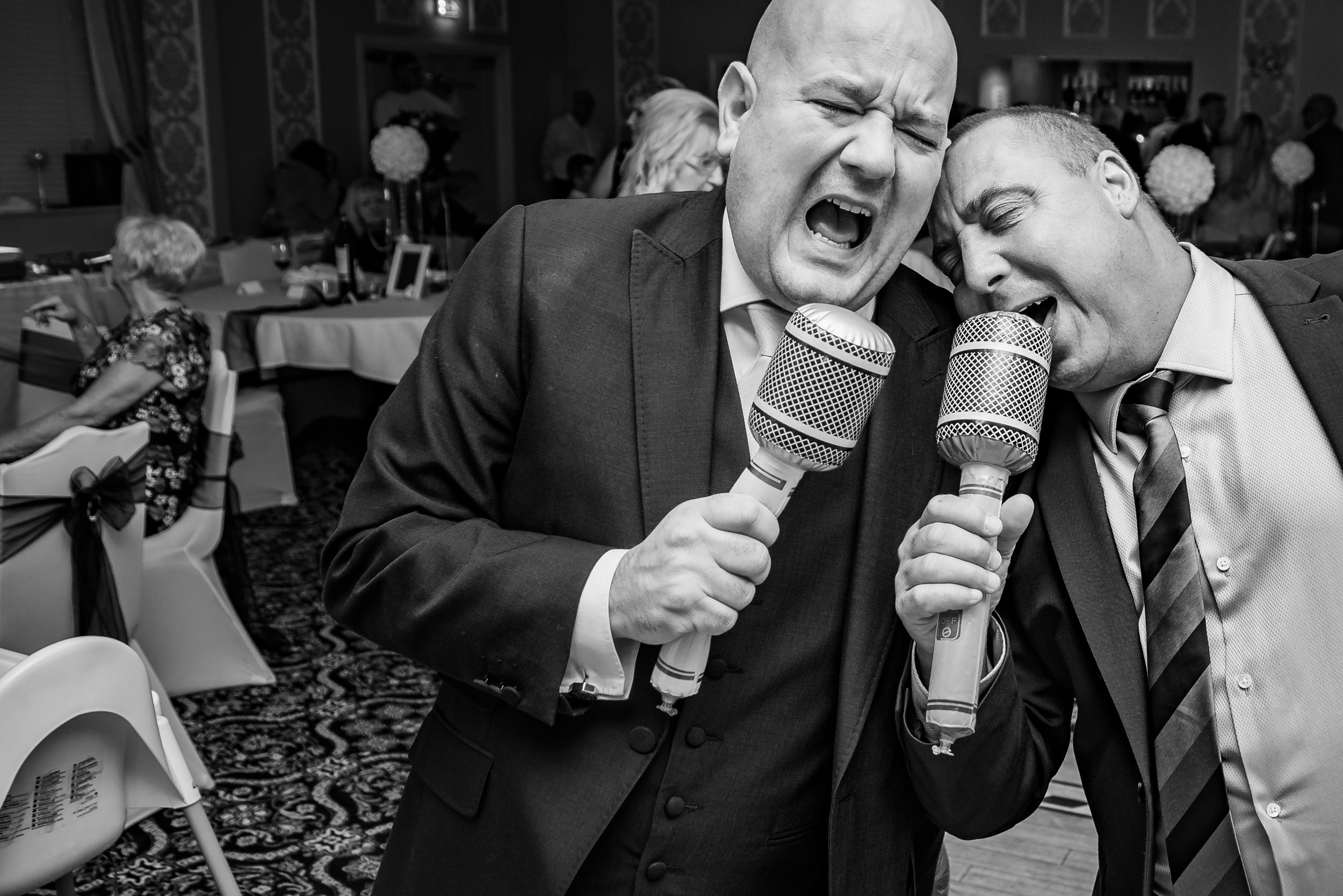black and white wedding photography groom and guest have something to sing about