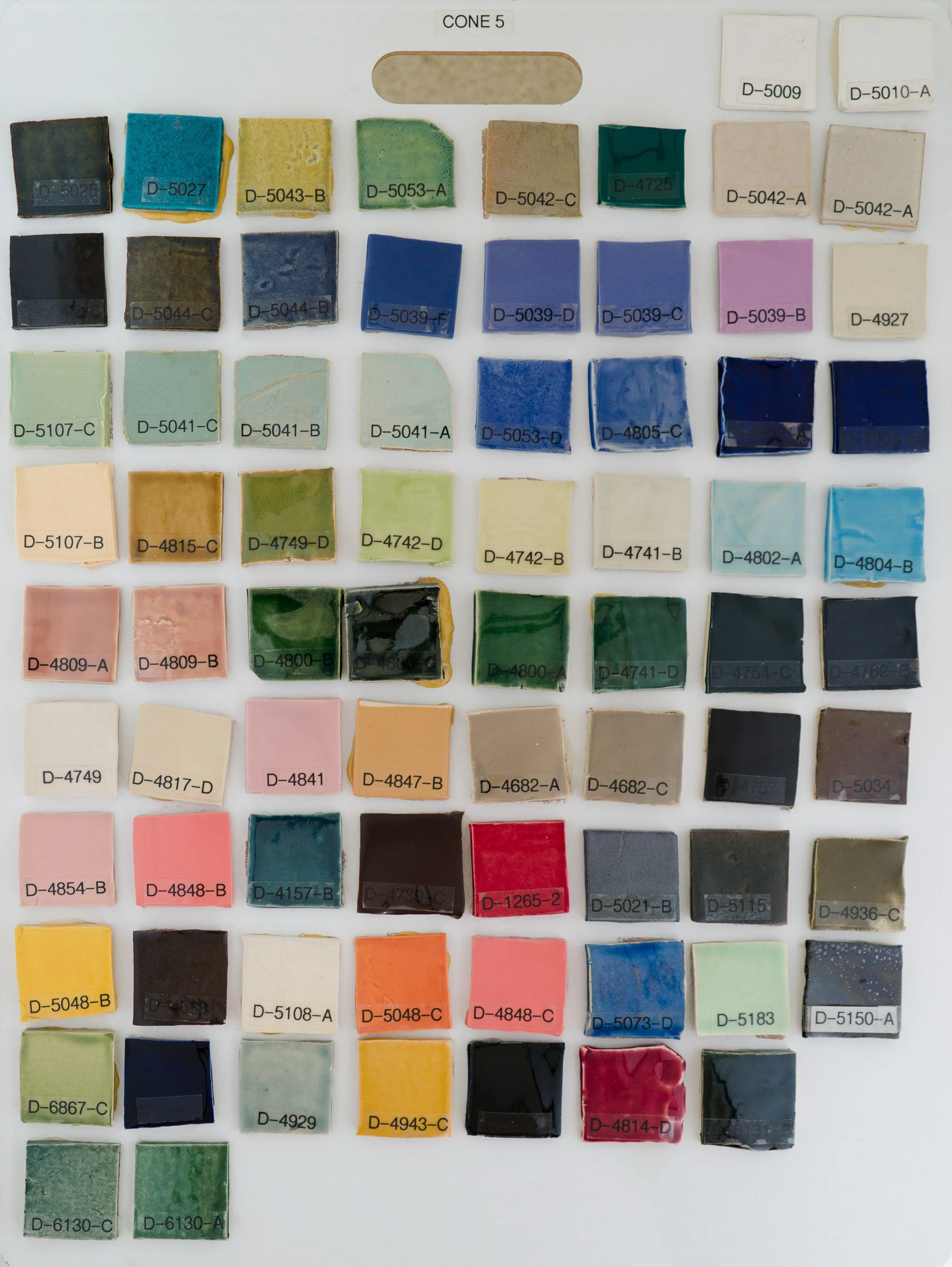 Sample tile board showing Cone 5 glazes on Bee Mix clay body (Codes D-5009 to D-6130-A).
