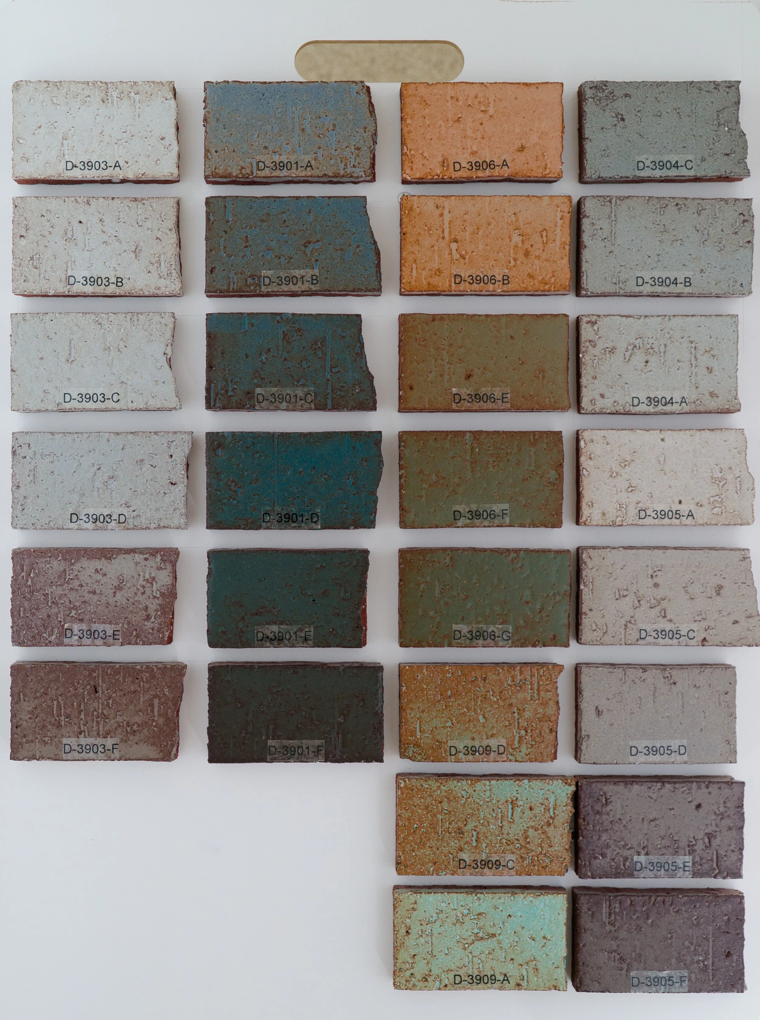 Sample display board showing Character Glazes fired on Red Brick body at Cone 05. Codes ranges include D-3903-A to D-3905-F.