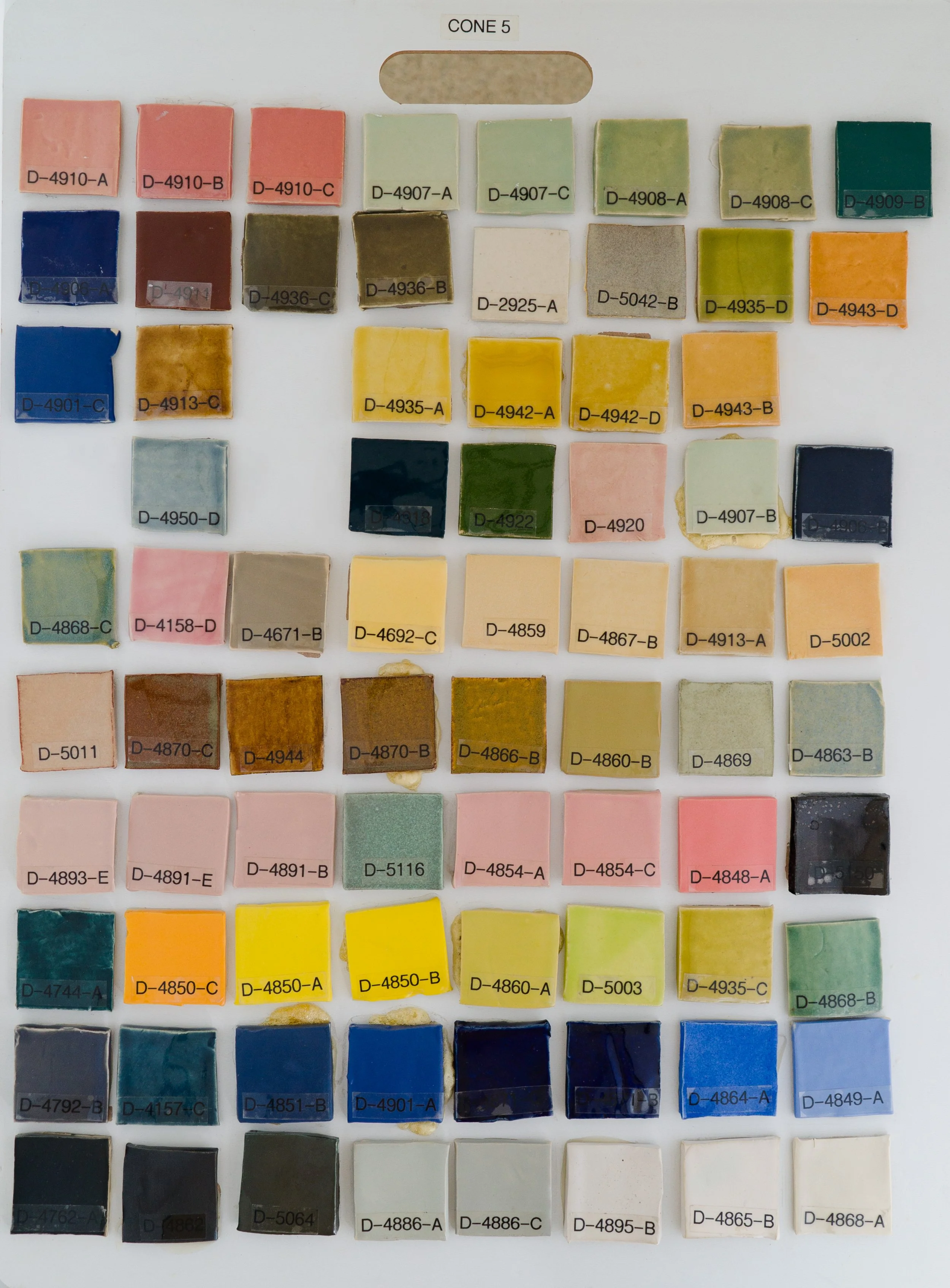 Sample tile board showing Cone 5 glazes on Bee Mix clay body (Codes D-4910-A to D-4868-A).