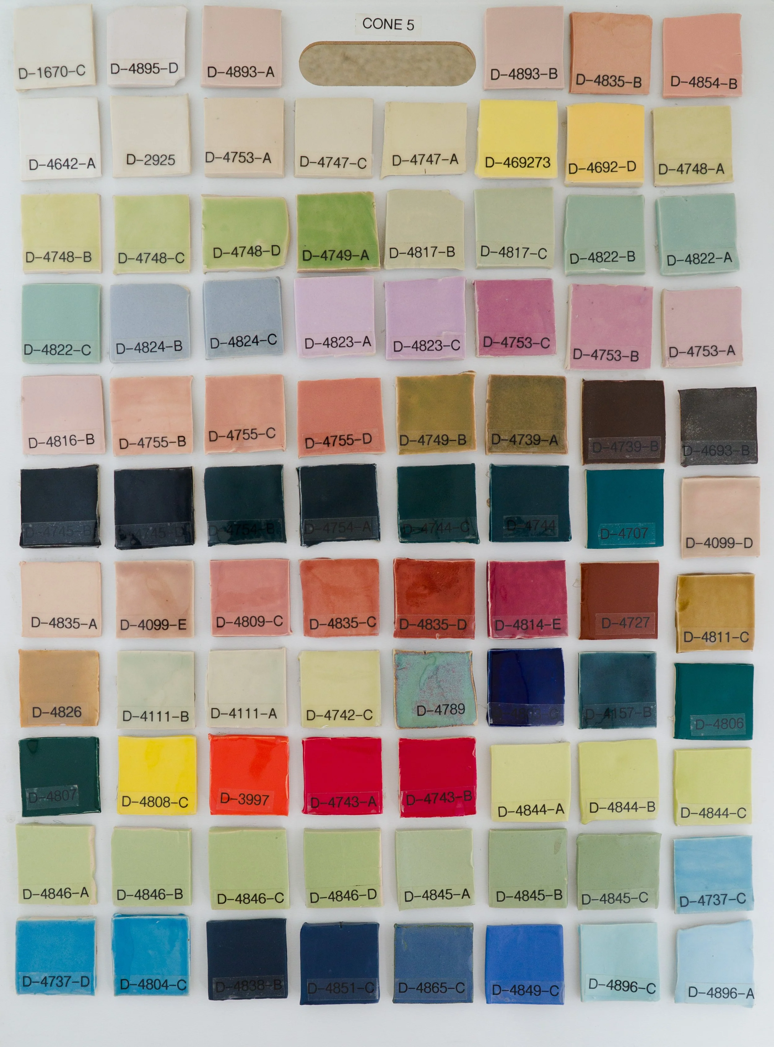 Sample tile board showing Cone 5 glazes on Bee Mix clay body (Codes D-1670-C to D-4896-A).