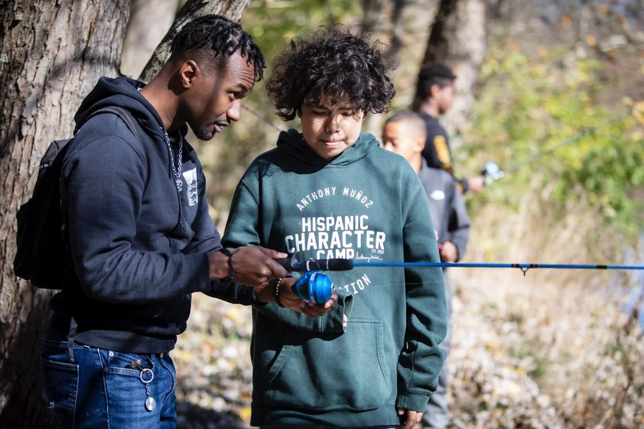 Antonio Howell, an advisor from Roberts Academy, helps a Crew teen with fishing.