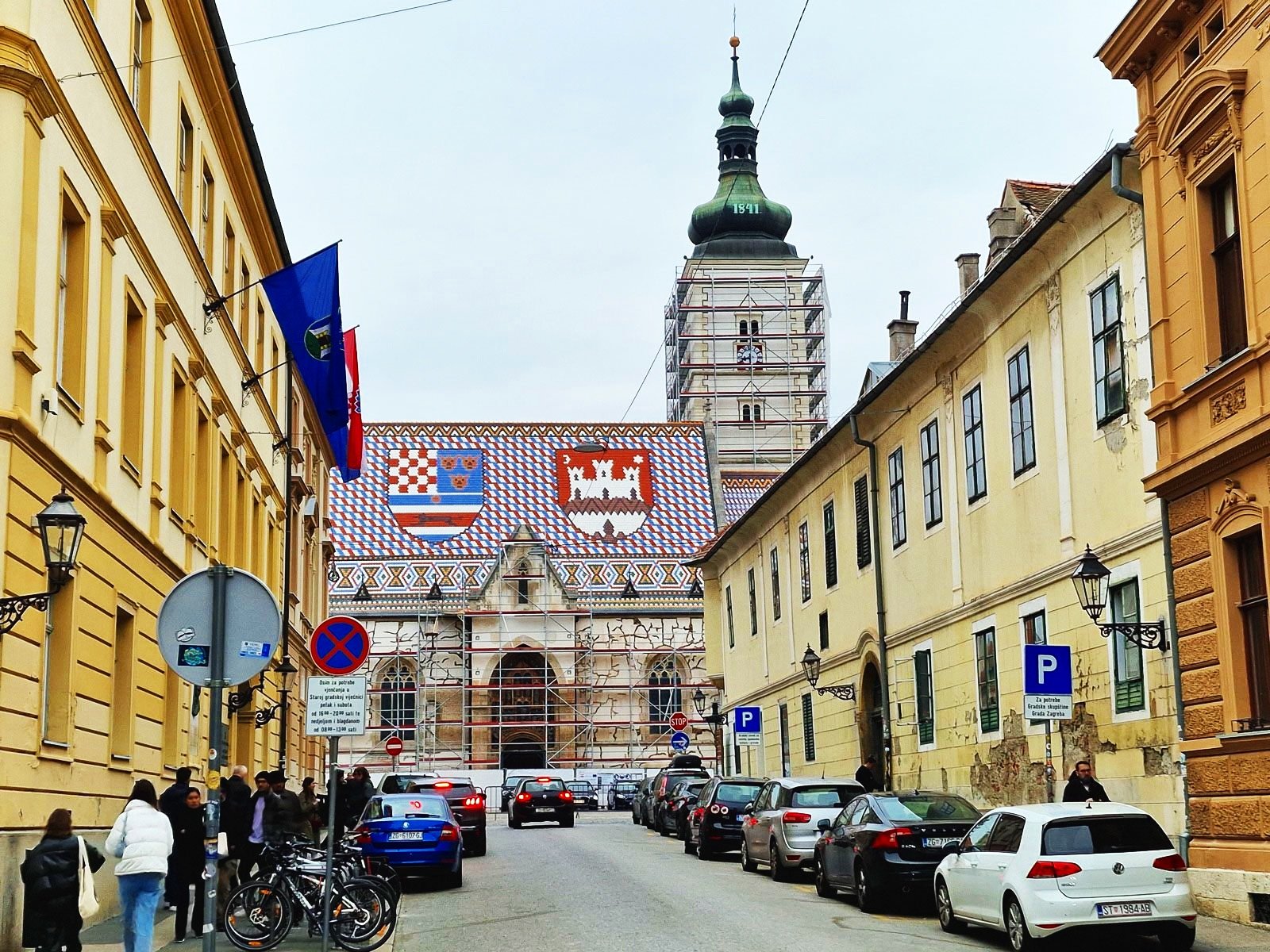 a church with a colourful tiled roof showing two coats of arms in zagreb