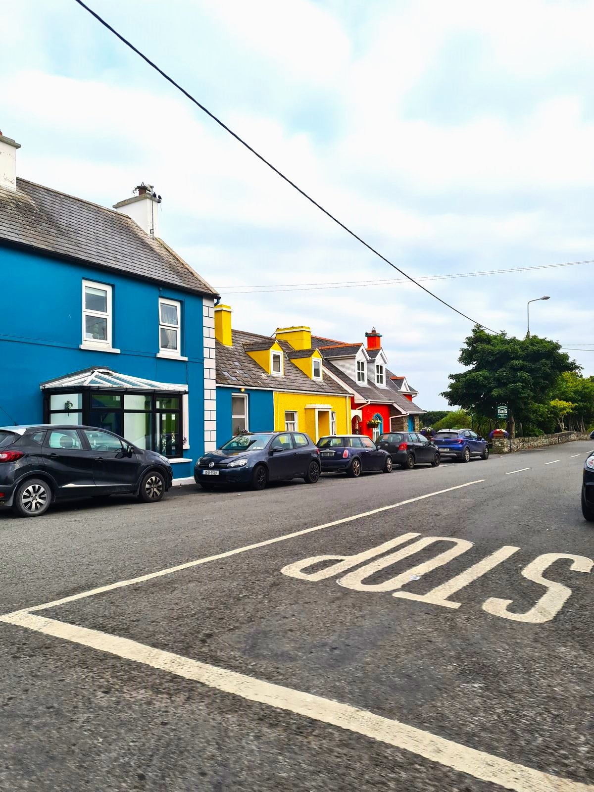 Road with a red, yellow, and blue houses next to each other