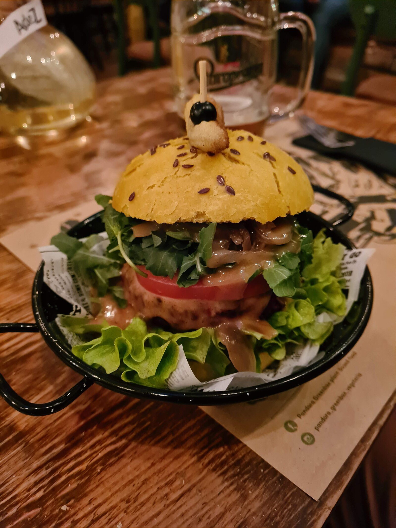A large burger filled with many colourful incidents on a wooden table