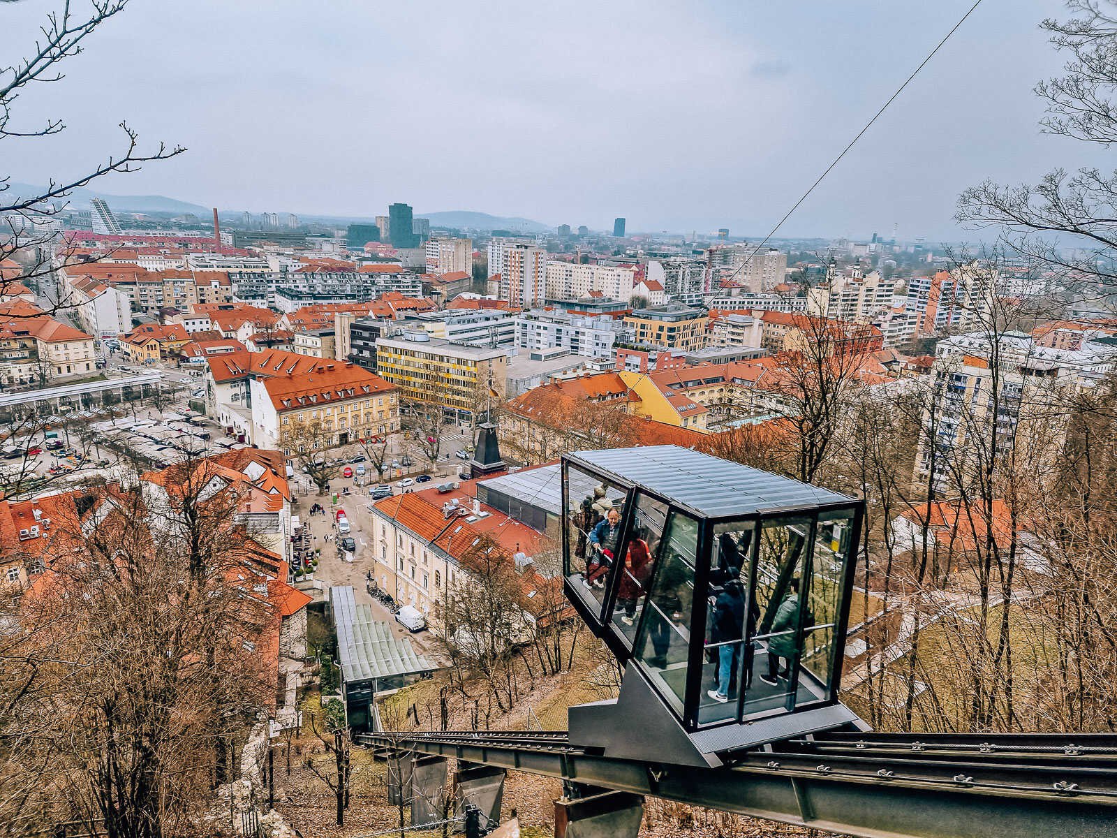 a glass funicular rising up the side of a hill with view of the city below