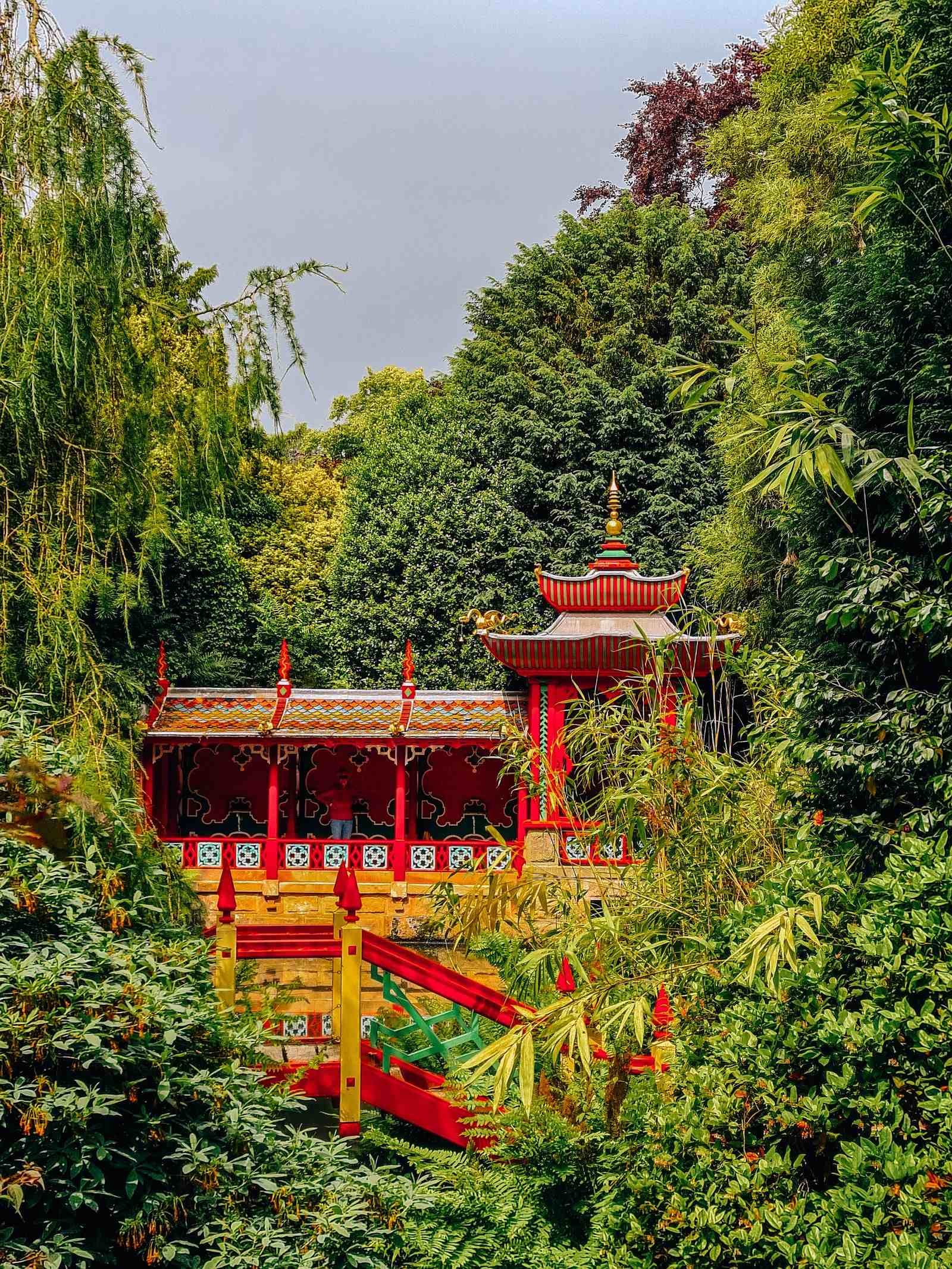 an asian style red and yellow pagoda surrounded by greenery in lush gardens at Biddulph Grange National Trust on a day out near Nottinghamshire