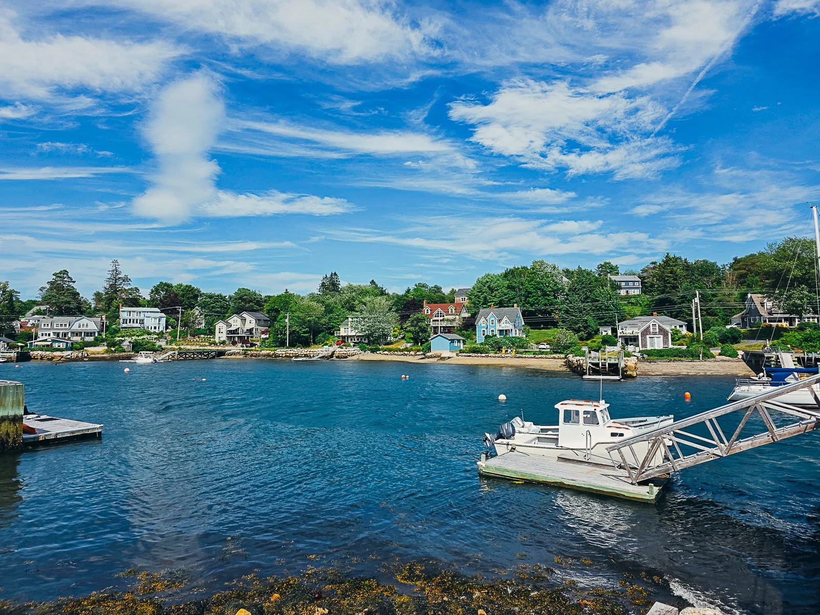 A calm harbour lined with clapboard colourful houses with small docks.