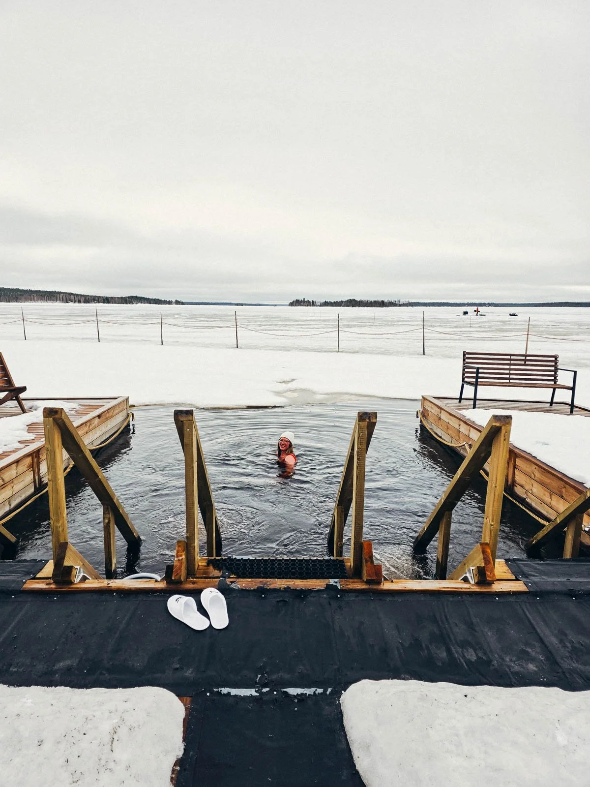 Helena swimming in a square hole cut into the ice of a frozen lake to plunge into after the sauna, arctic plunge is one of the best things to do in Rovaniemi