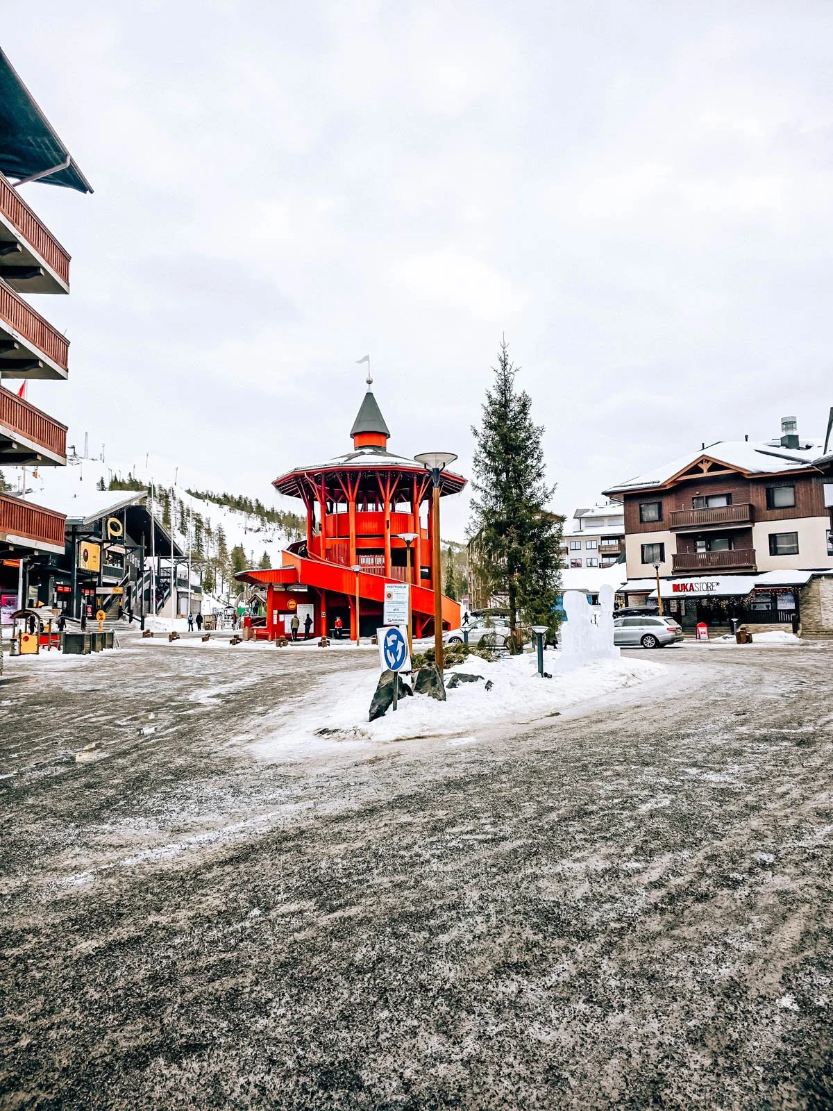 A large gravel and snow coved road with a tall red tower in the background at Ruka ski resort in Finnish Lapland