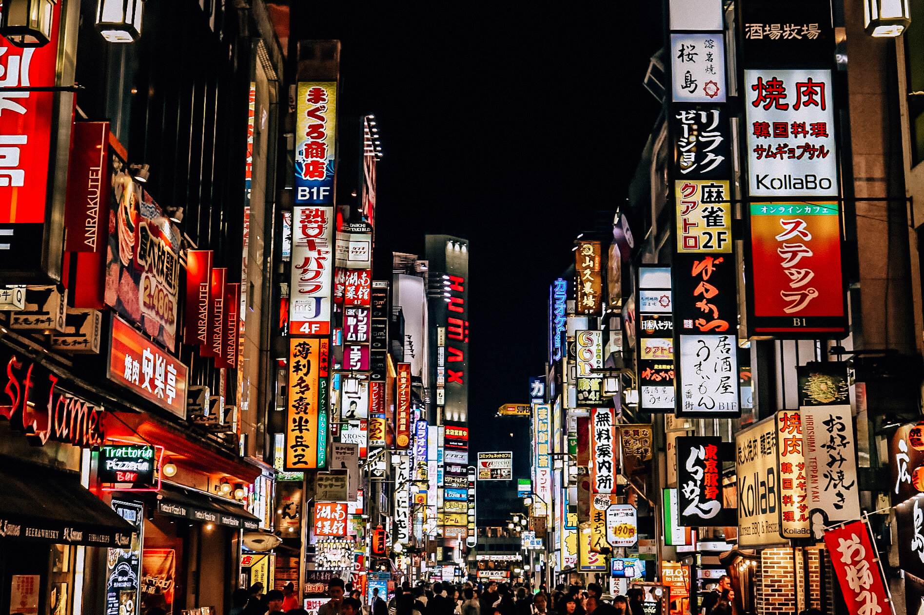 Many bright signs on shops lining a busy Japanese street at night