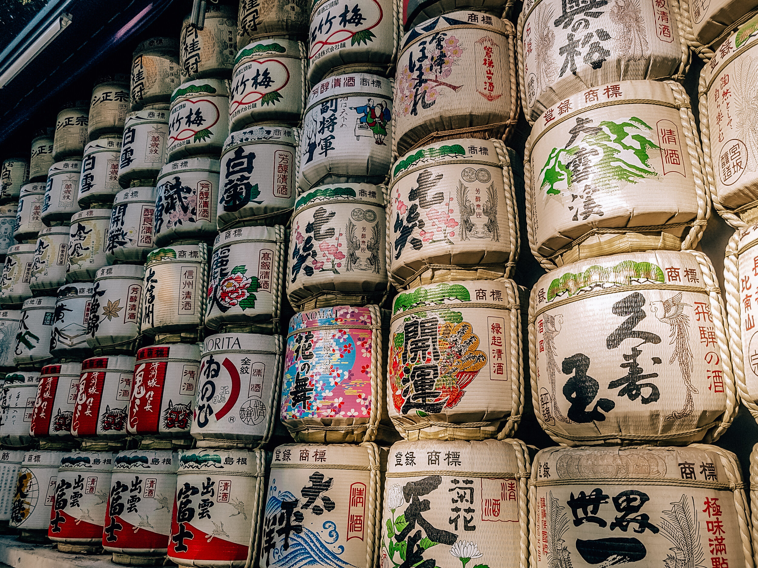 Many large colorful sake barrels stacked on top of each other