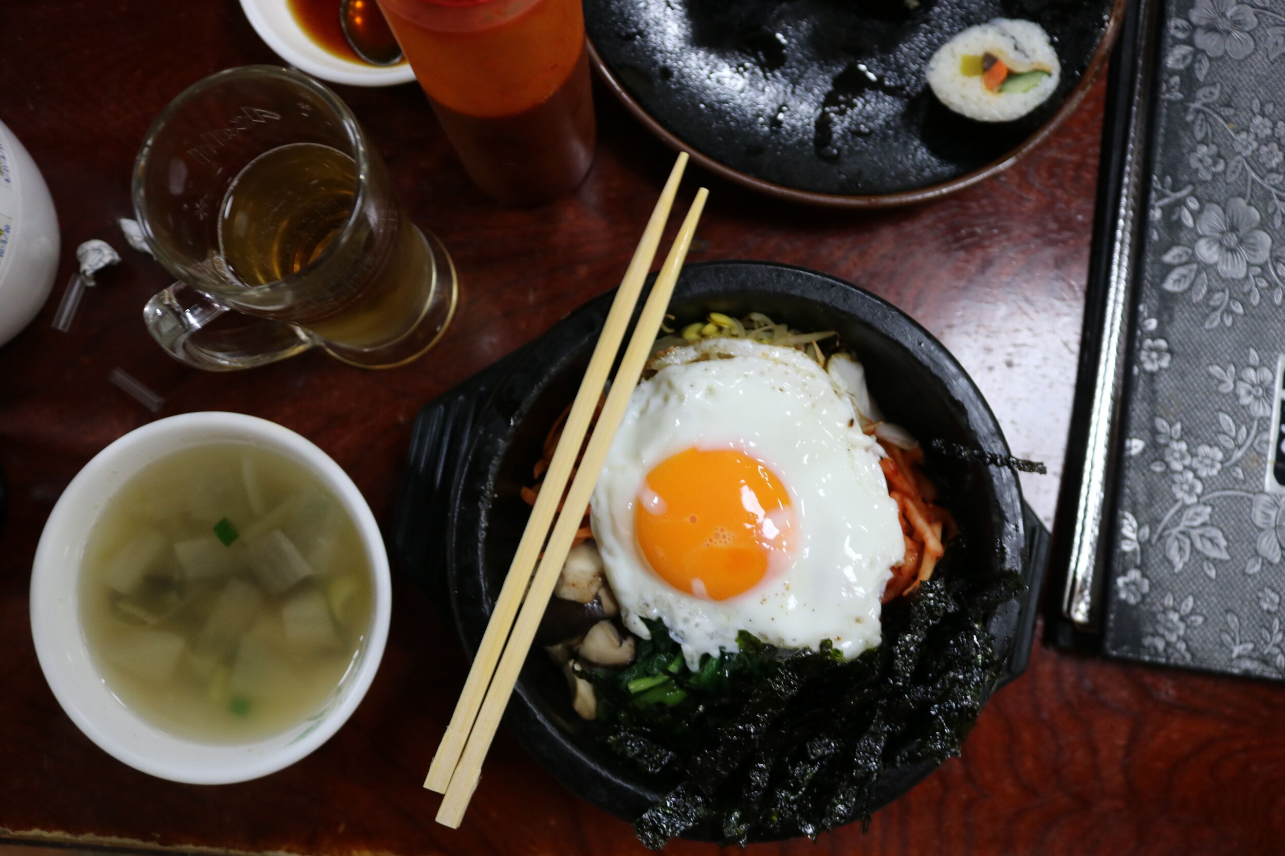 An egg in a bowl with wooden chopsticks resting on the top