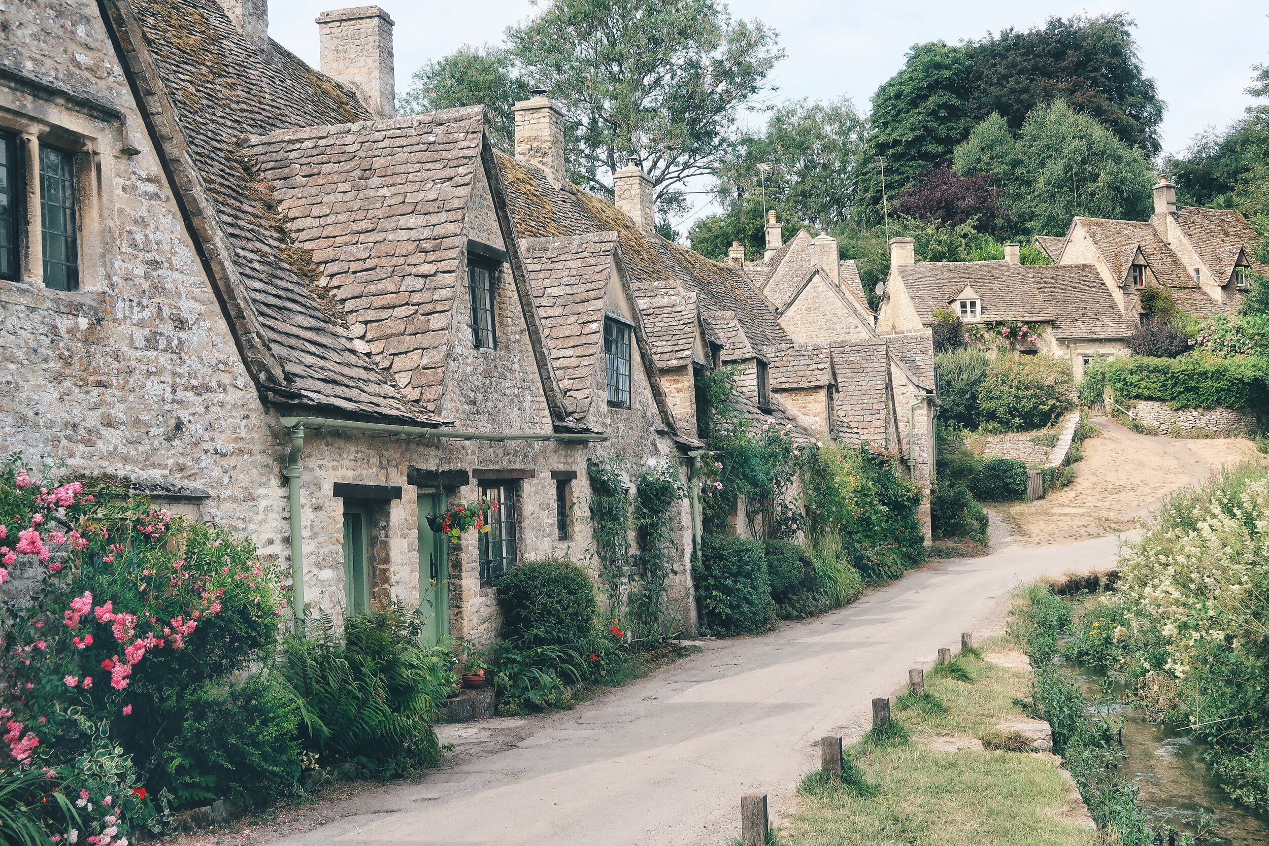 The famous Arlington Row in Bibury, Cotswolds. Stone houses line a small street with slate roofs and quaint architecture
