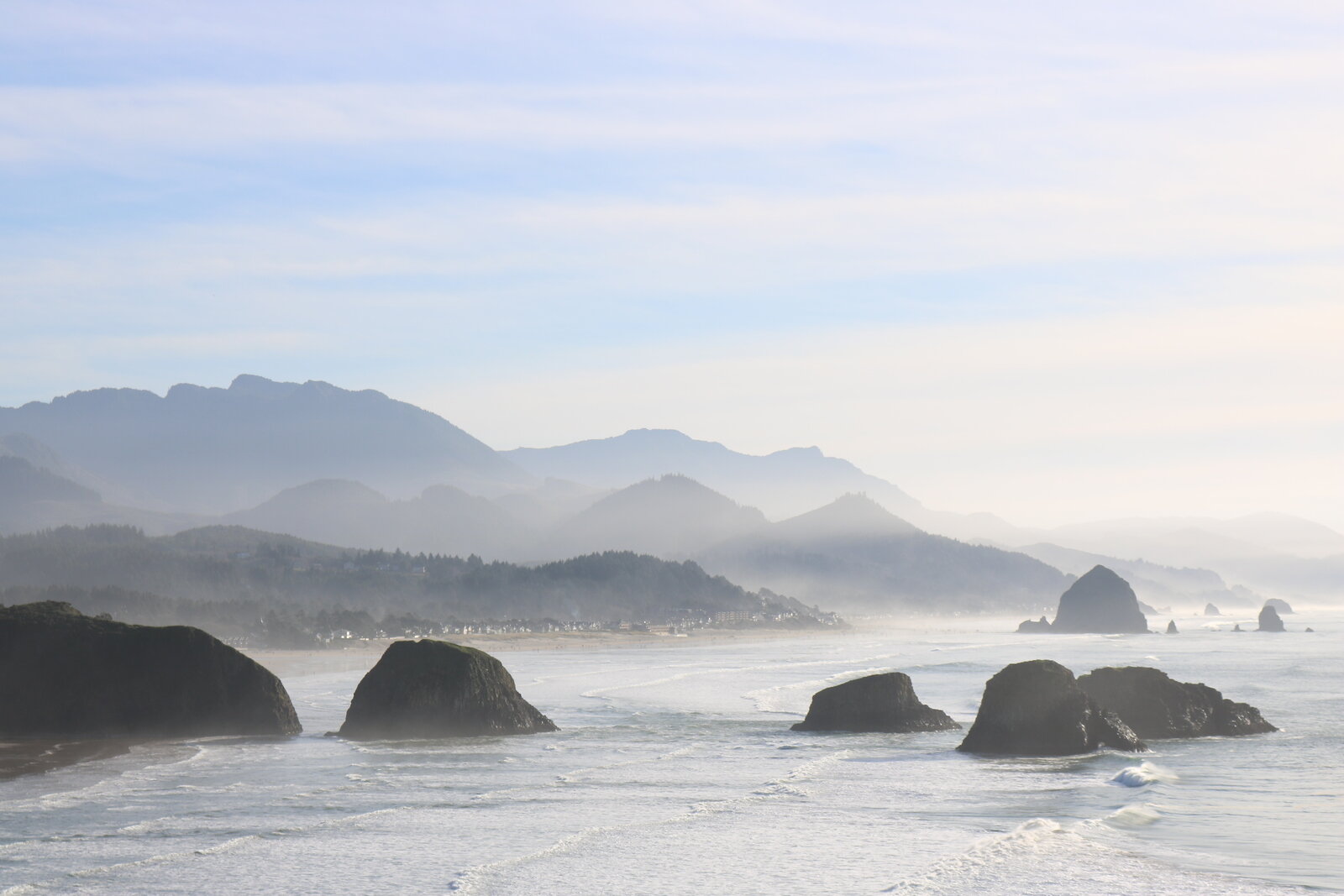 A panoramic view of the coast with low mist over the rocks jutting from the sea atEcola State Park viewpoint