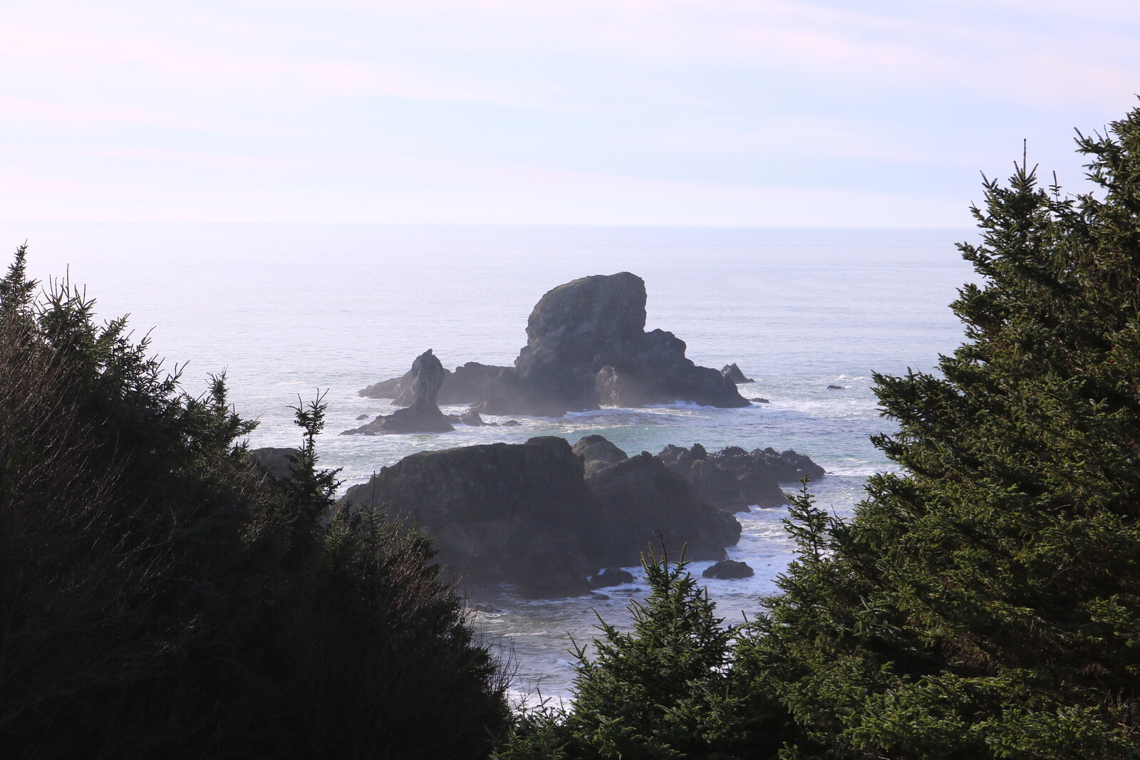 A dark rock jutting out of the ocean just off the coast at Ecola State Park viewpoint