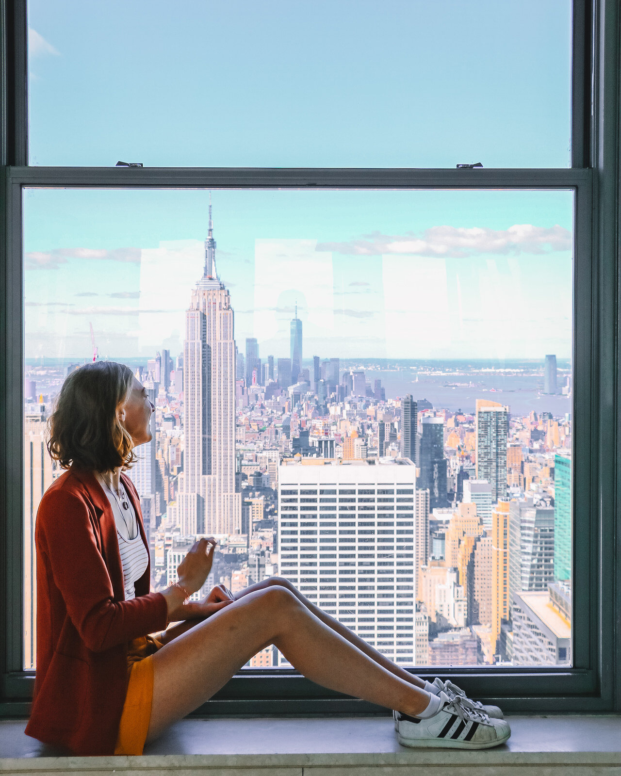 Girl in front of a window with a view of the Empire State Building