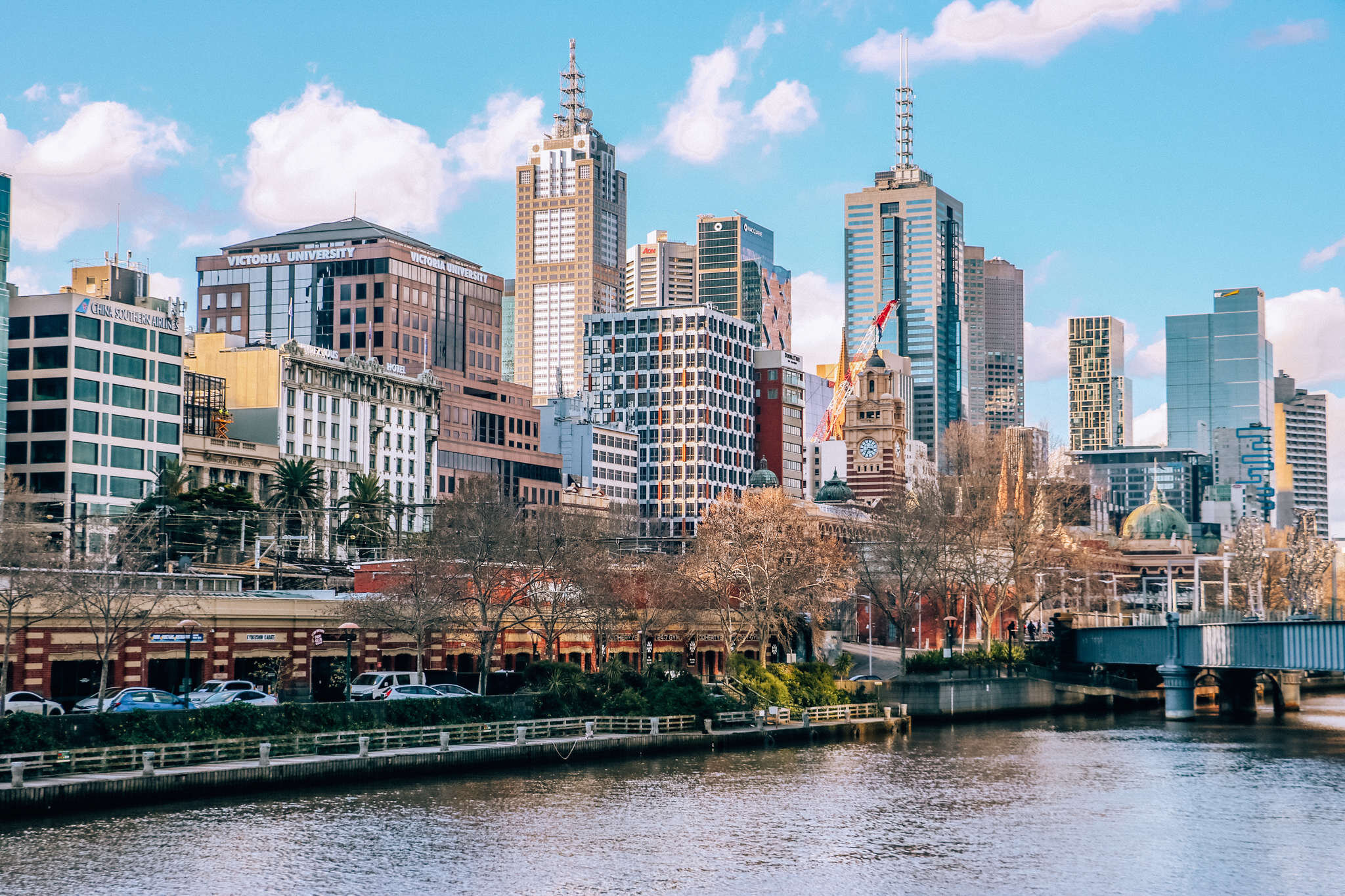 An across the river view of the Melbourne skyline with many tall buildings lining the rivers edge