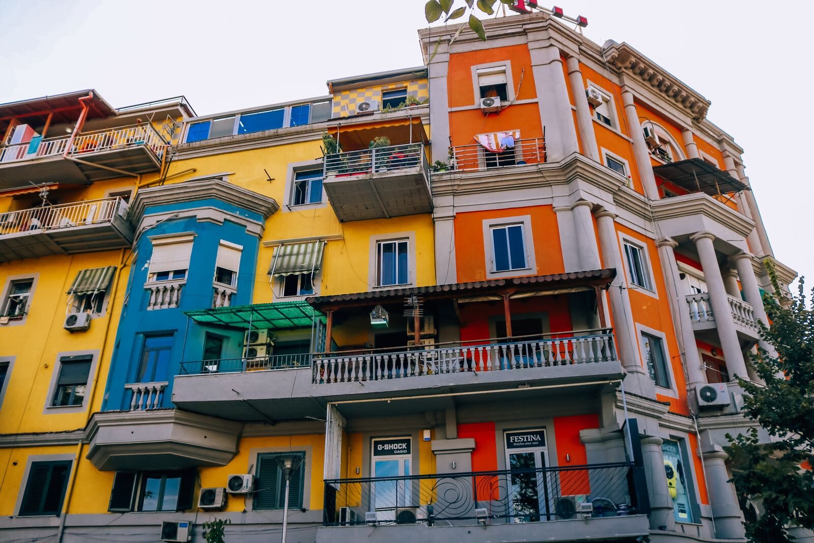 colourful painted buildings in Tirana, Albania. Yellow, blue and orange with grey balconies and columns at each window