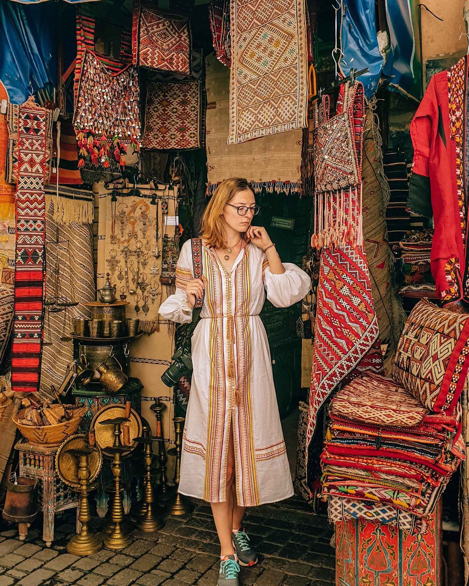 Helena standing in a souks shop surrounded by many patterned tapestries in Marrakesh medina