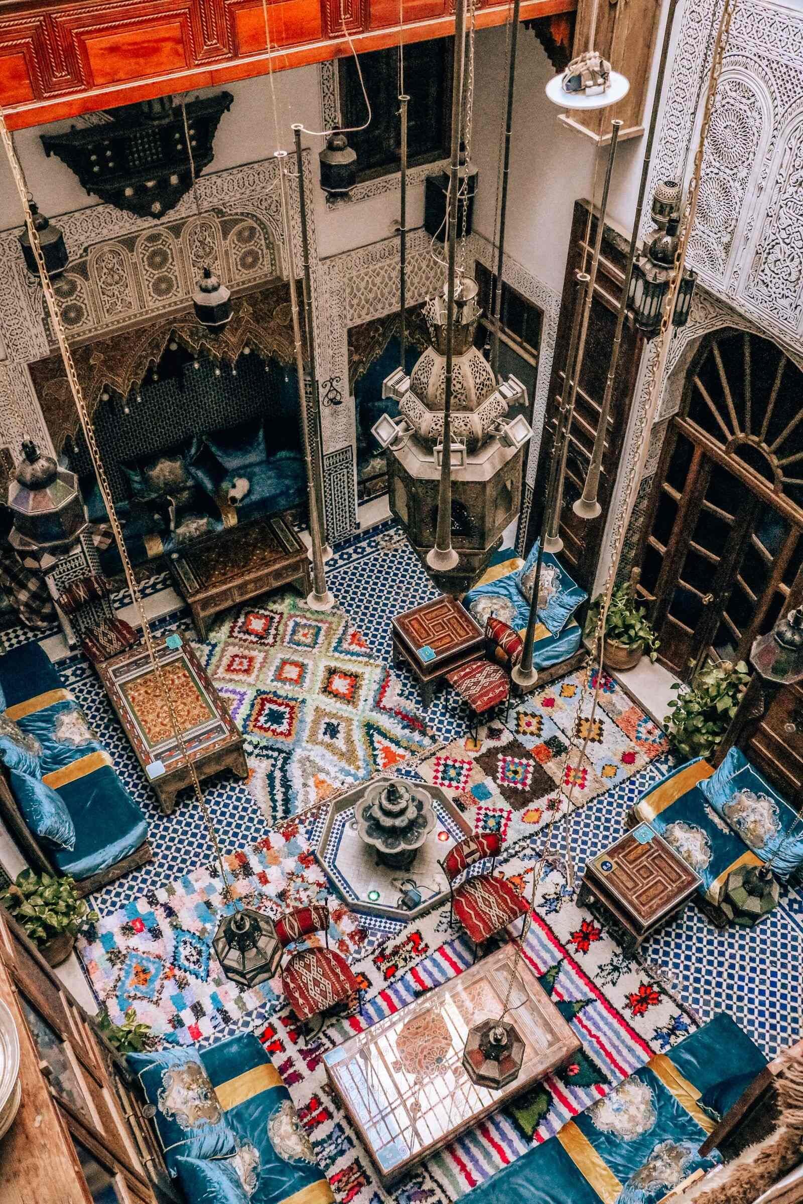 A top down view of a colorful room with many carpets and decretive ties at Riad Verus Fez hostel