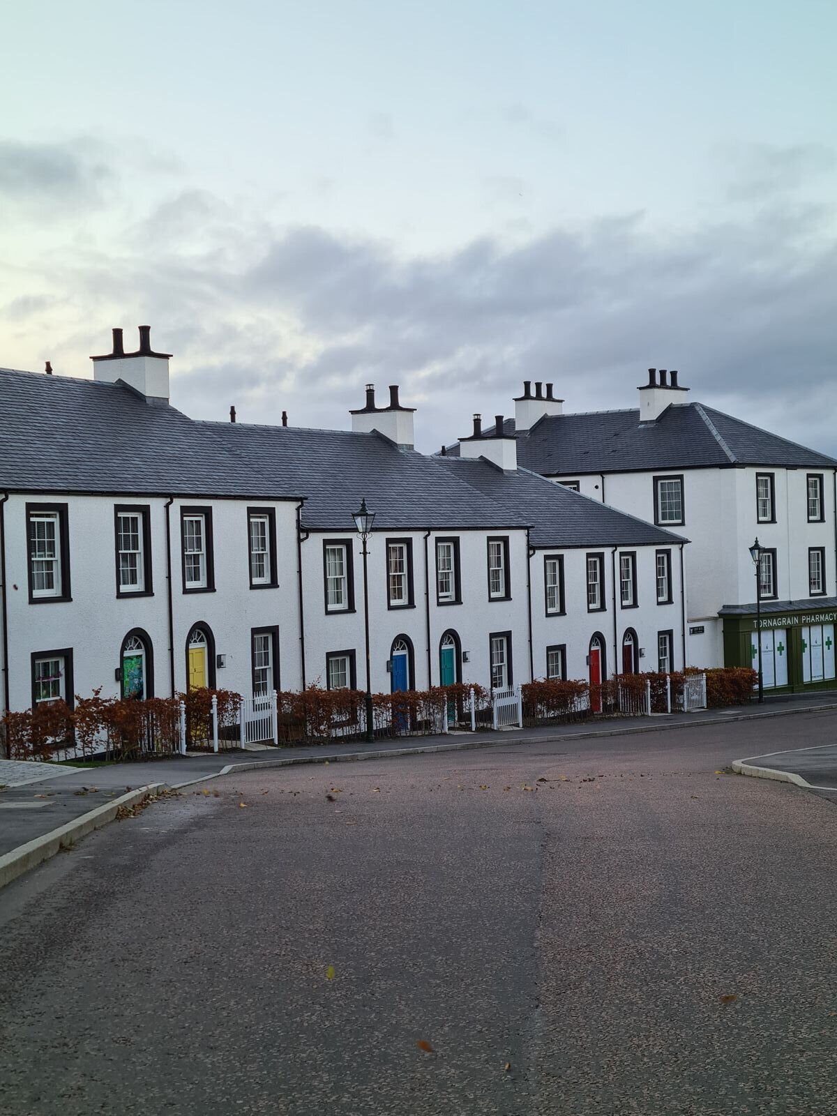 A row of white houses with colourful front doors on a street in Inverness, Scotland