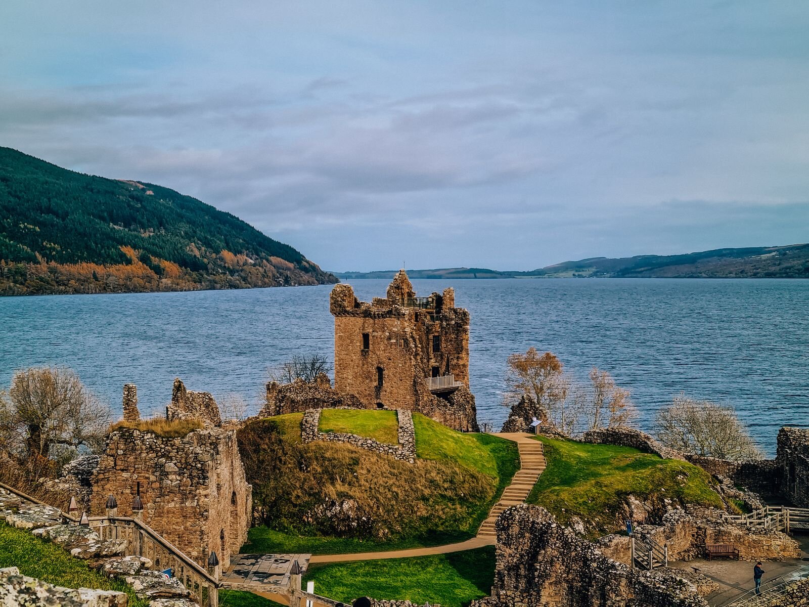 Castle ruins of Urquhart Castle on Loch Ness Scotland. The ruins are at the top of a grassy slope with the loch behind it