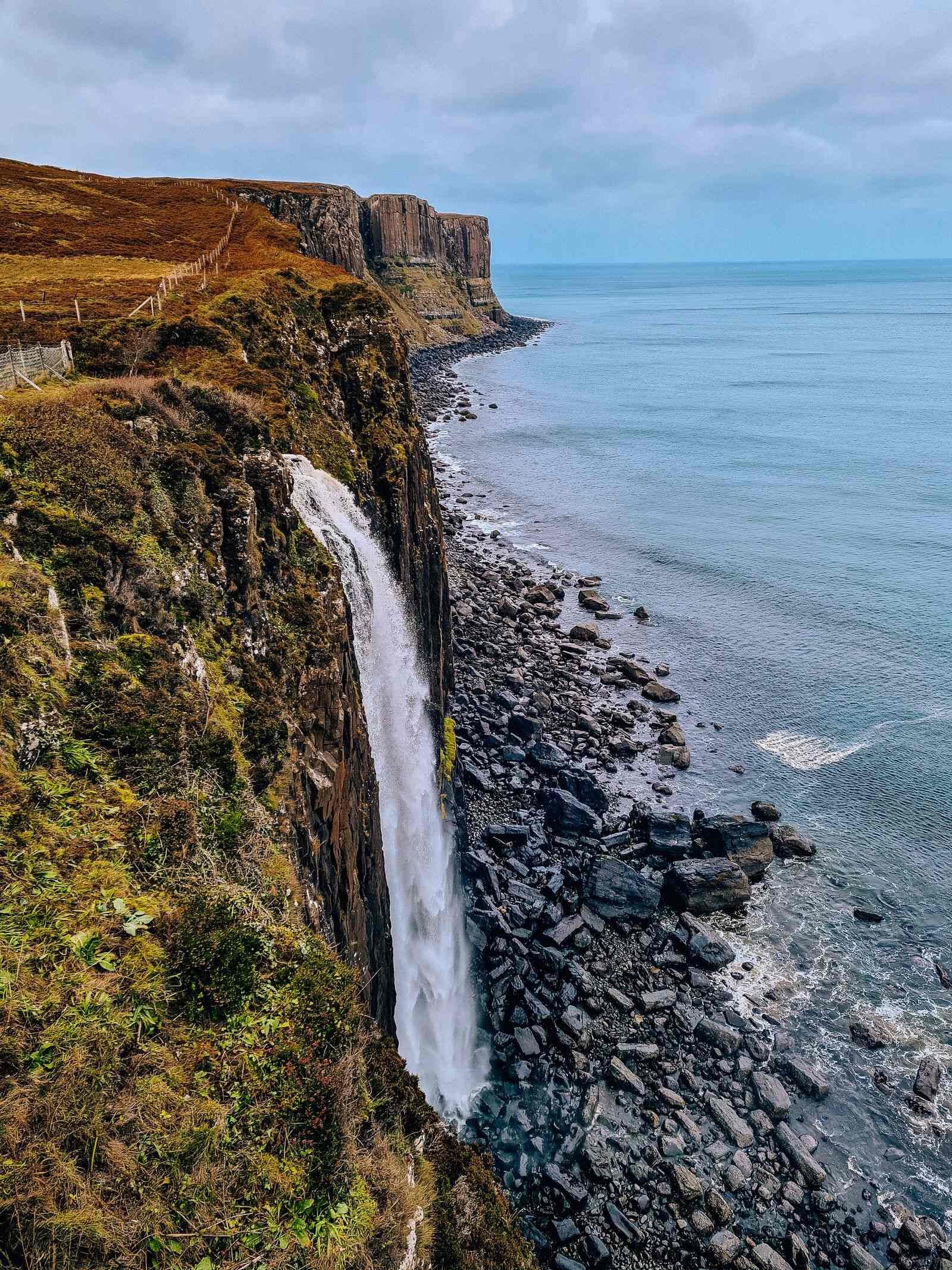 A waterfall falling from a grassy cliff into the sea