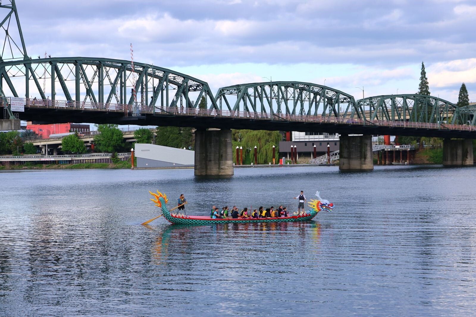 A colorful Dragonboat in the water with a bridge in the background at the Portland waterfront