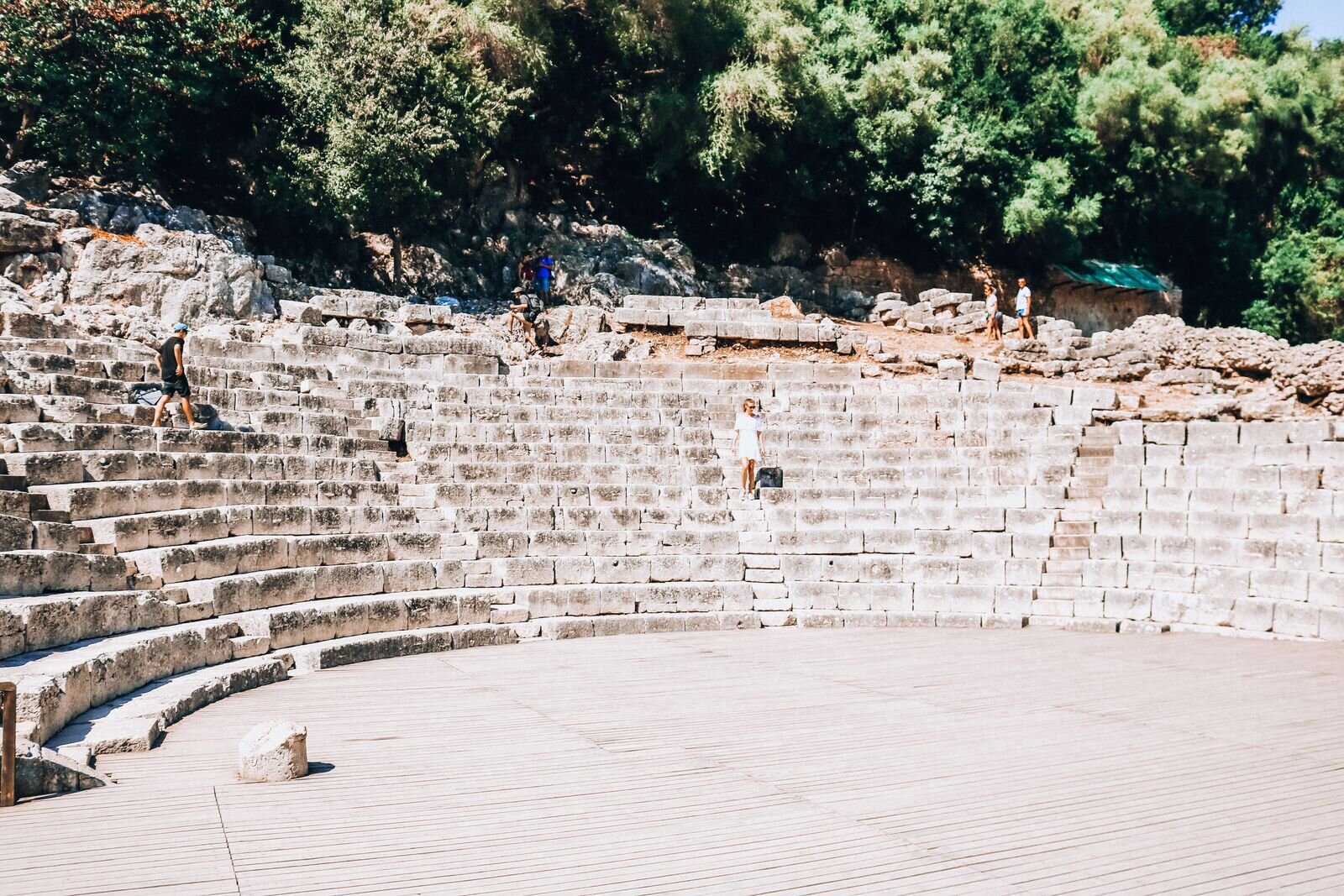 Helena in white walking down the stone steps of a ancient stone amphitheatre in Albania
